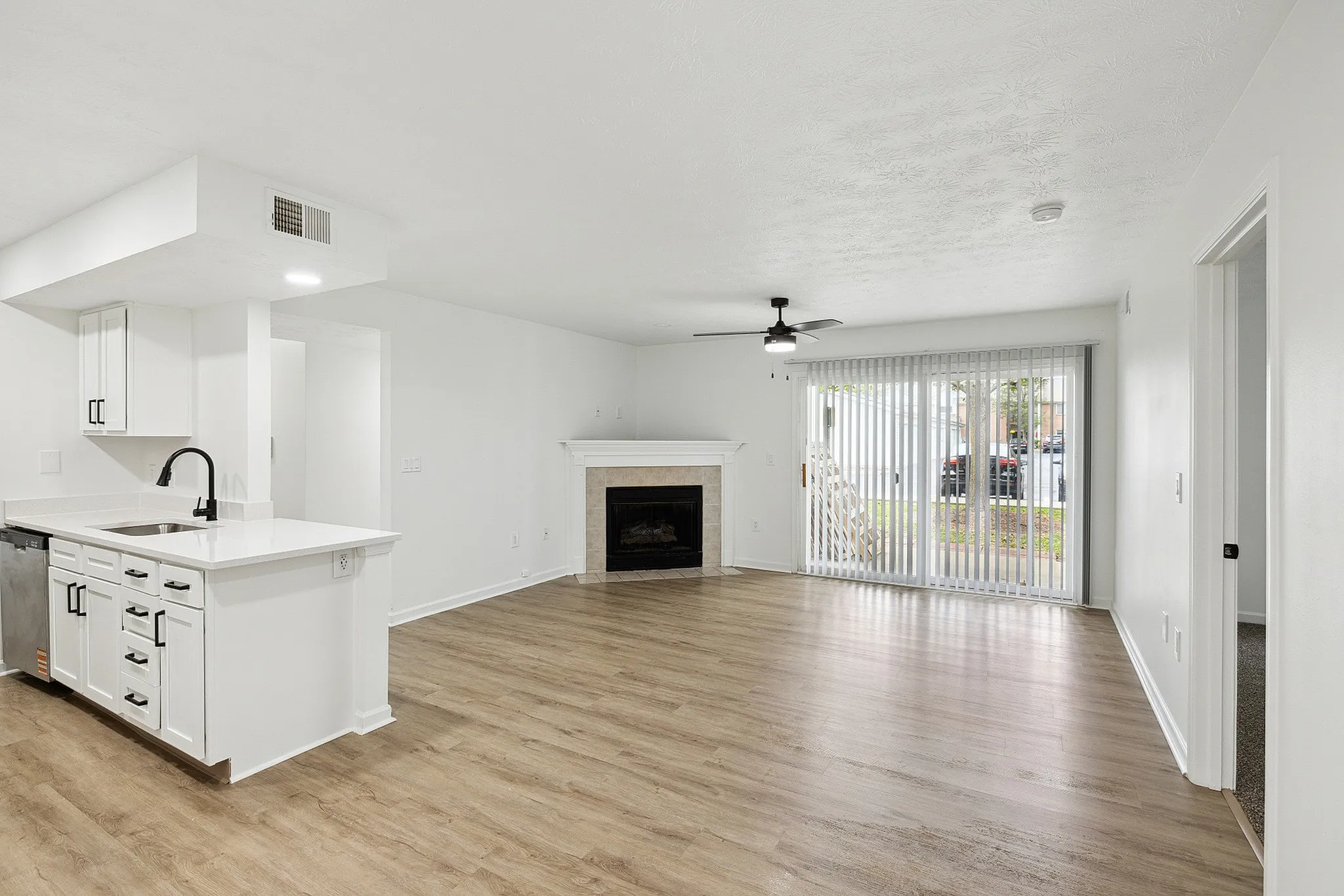 Bright and airy open-concept living space featuring elegant hardwood floors, a modern kitchen with sleek white cabinetry, and a cozy fireplace.