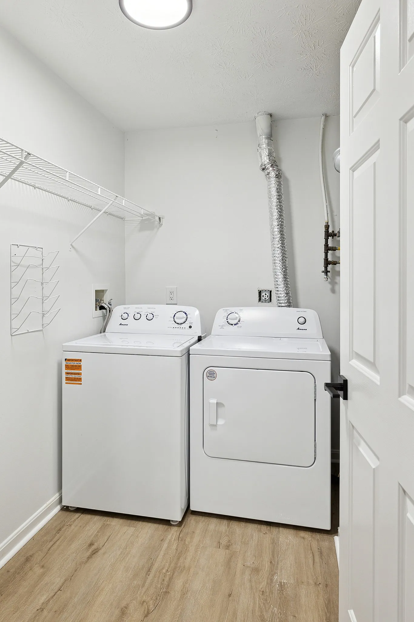 Modern laundry room with efficient washer and dryer, featuring sleek white appliances and elegant wood flooring.