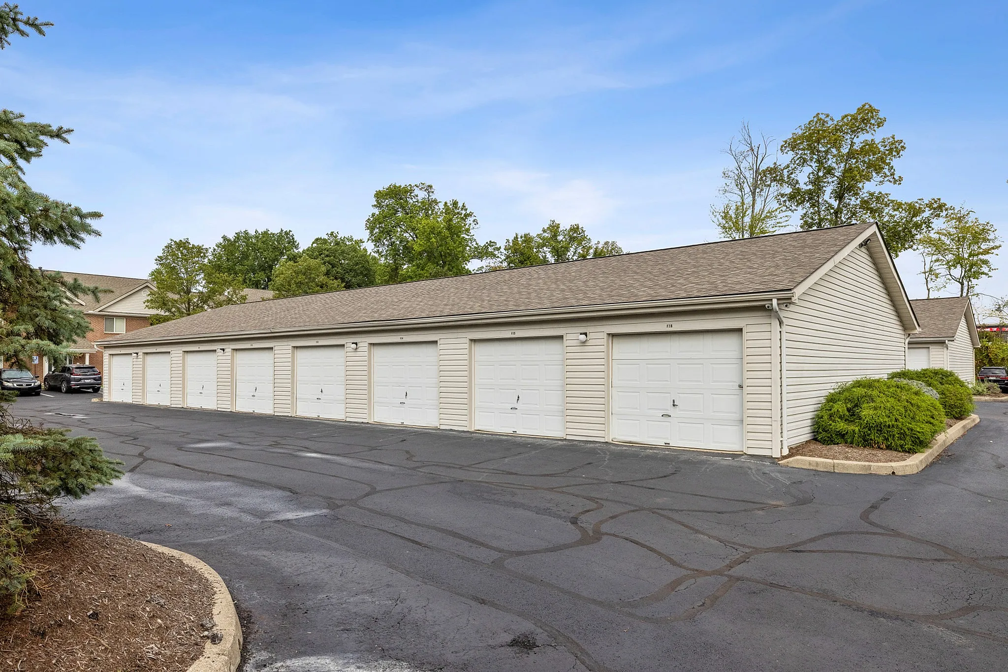 Spacious apartment complex with multiple secure garages, surrounded by lush greenery and a serene ambiance.