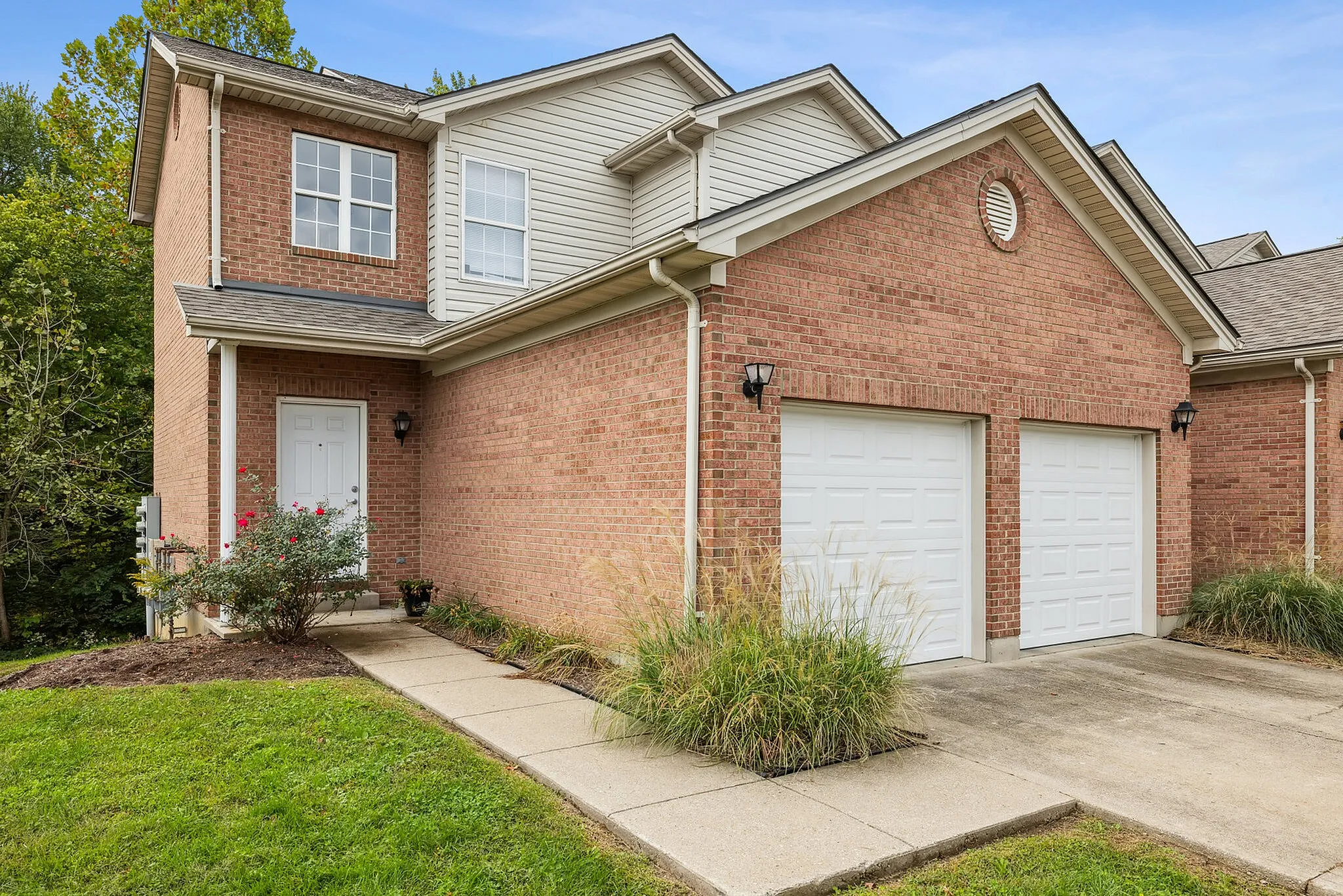 Charming suburban home with a red brick exterior, double garage, and well-maintained front yard landscape.