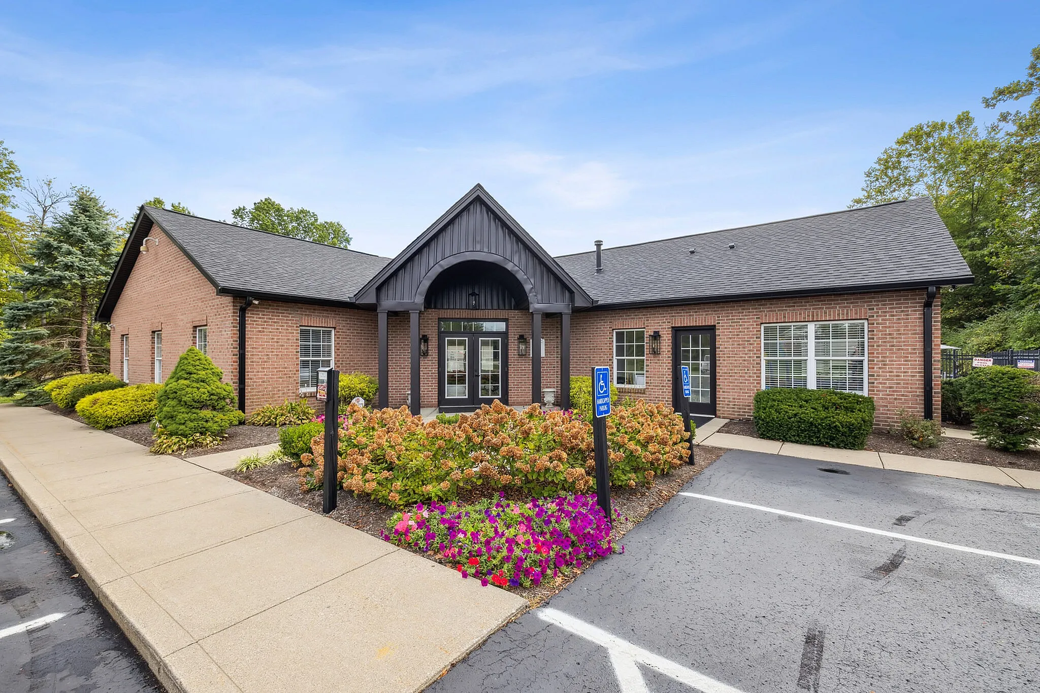 Charming brick community center with beautifully manicured landscaping and ample parking.