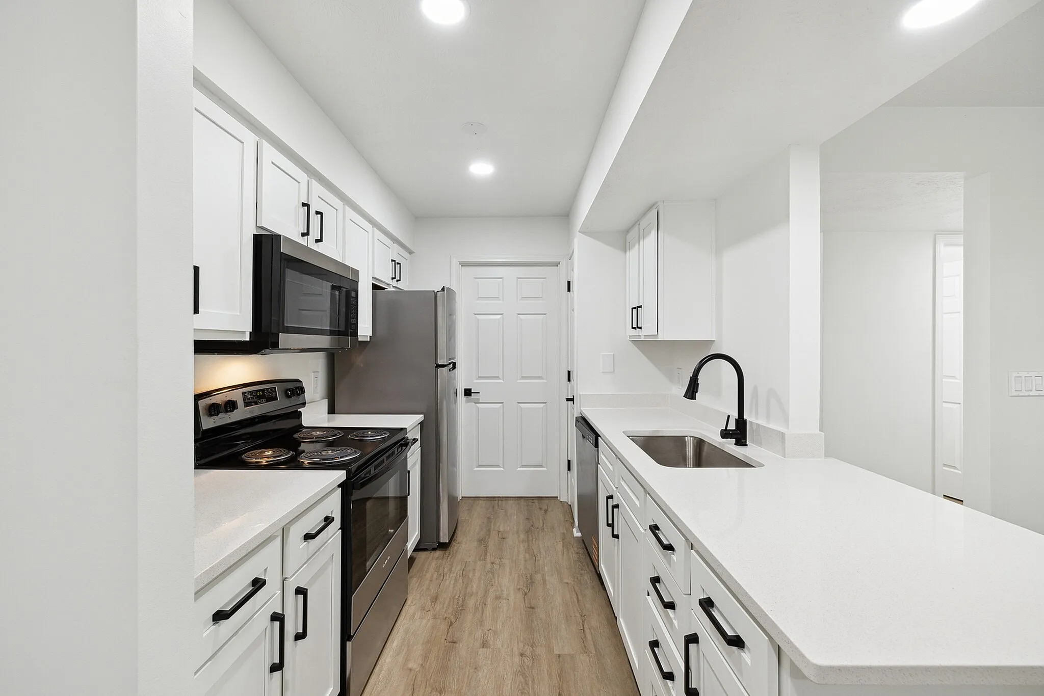 Modern kitchen with sleek appliances, bright white cabinetry, and elegant countertops in an inviting open layout.