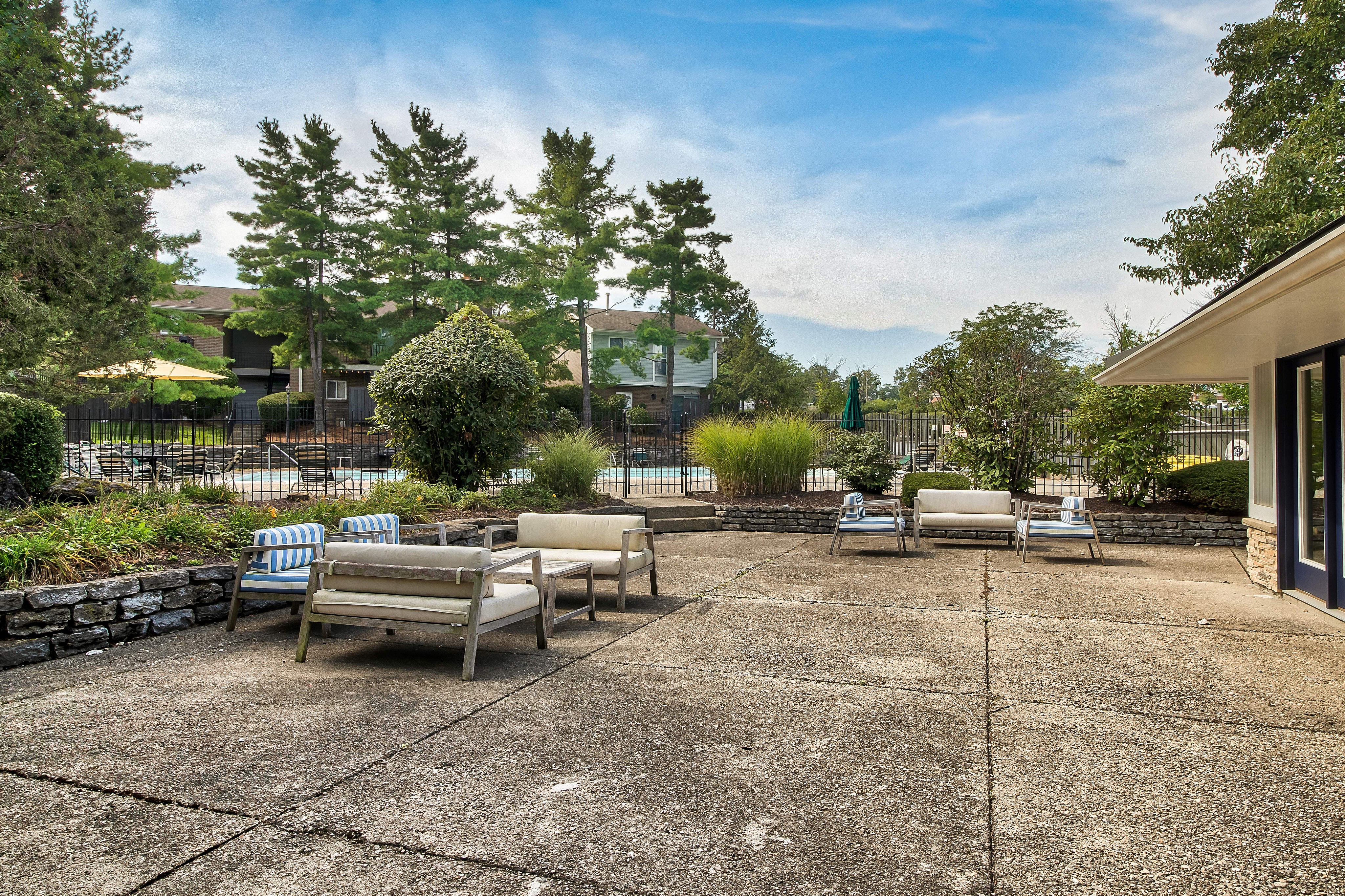 Inviting outdoor patio area with stylish seating, lush greenery, and a view of the swimming pool in a serene residential setting.