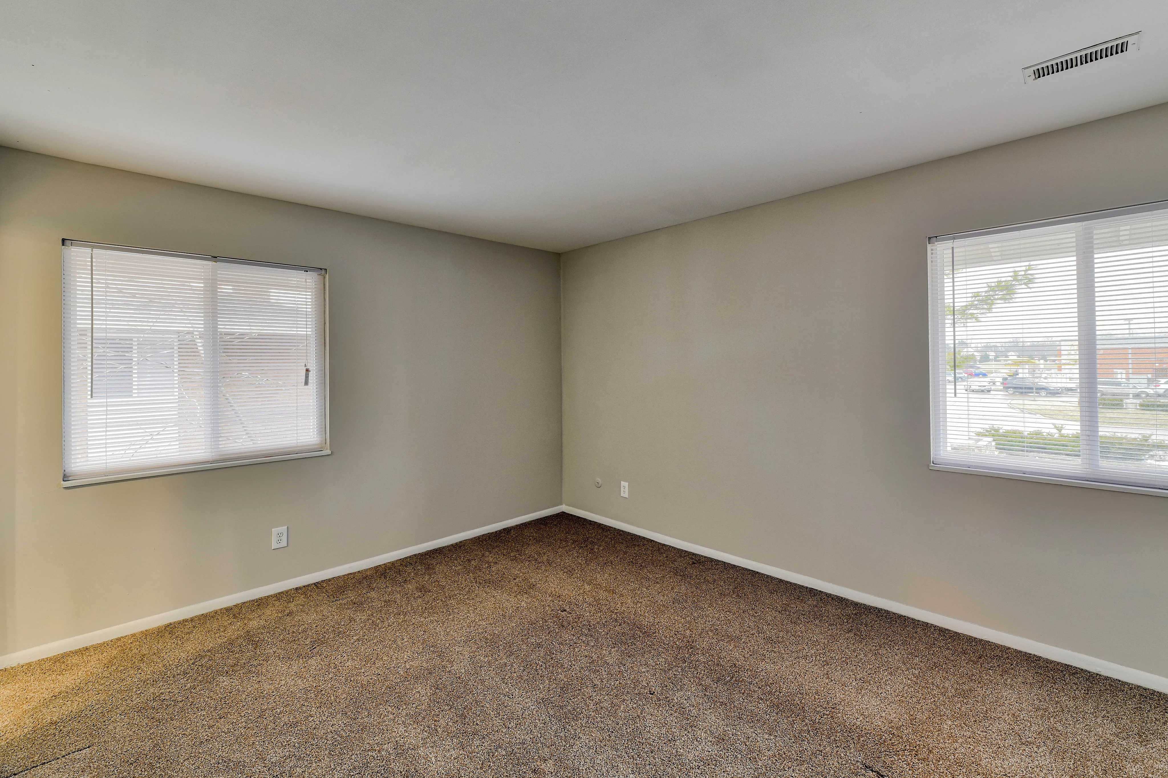 Bright and spacious room with large windows offering ample natural light and plush carpeting.