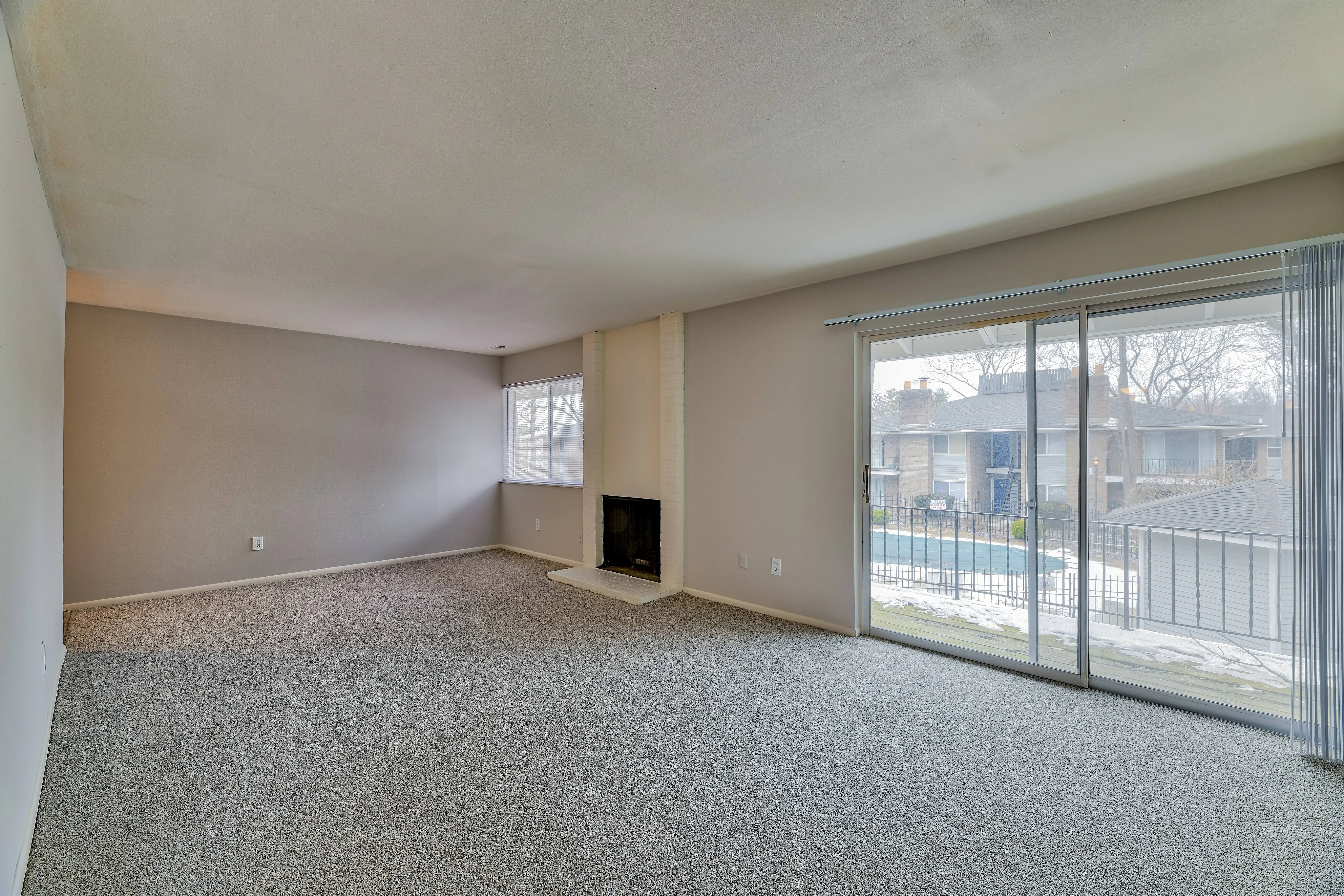 Elegant living room with plush carpet, cozy fireplace, and floor-to-ceiling windows offering scenic balcony views.
