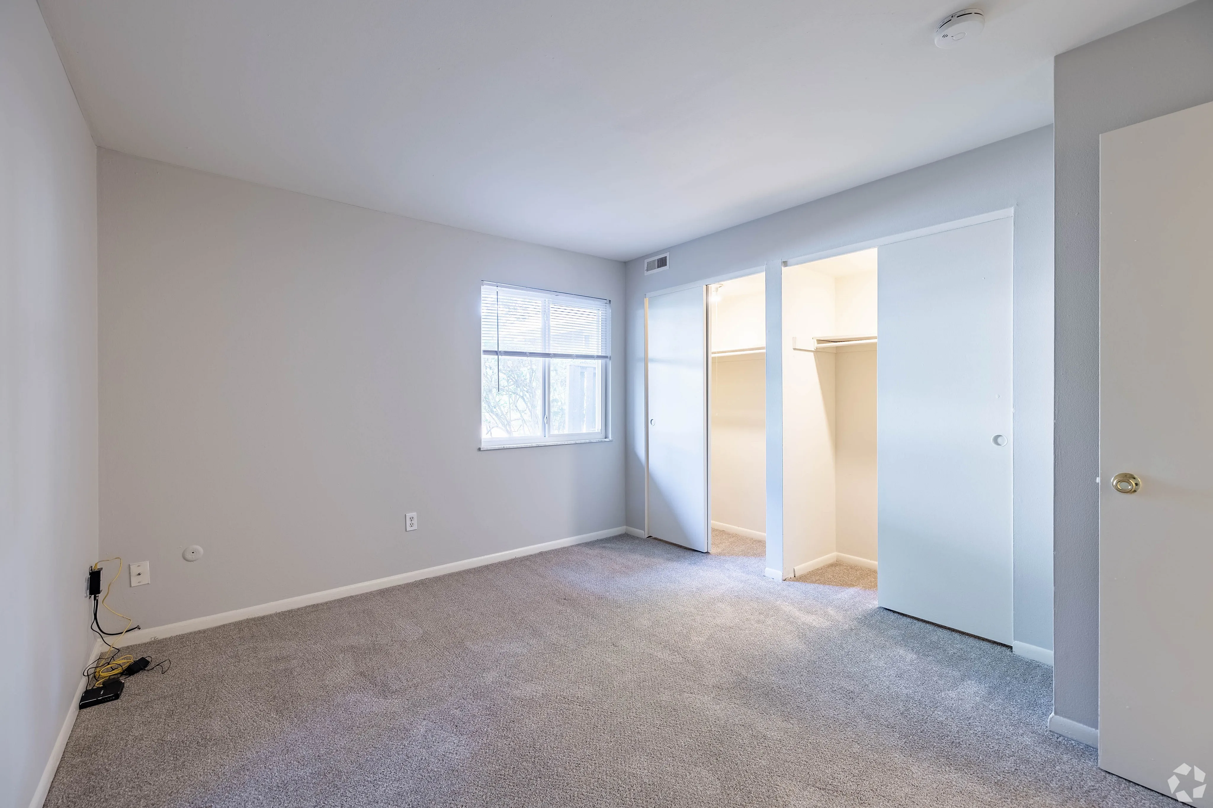 Bright and airy bedroom with plush carpeting, large window for natural light, and spacious dual closets.