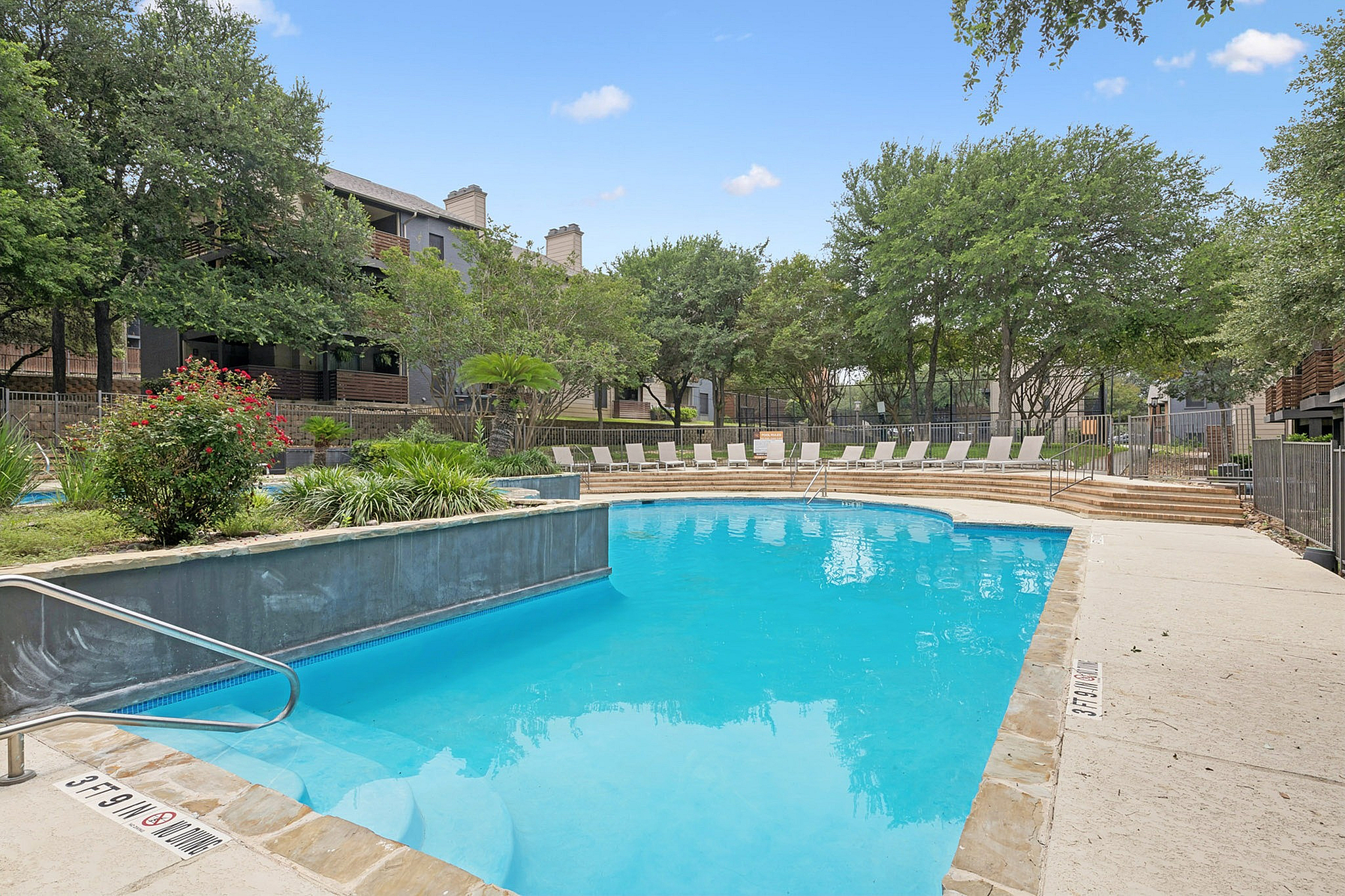 Inviting outdoor pool area with lush greenery and ample poolside seating, perfect for relaxation and leisure.