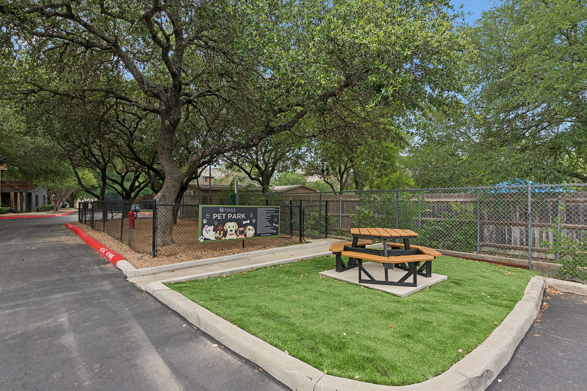 Charming pet park with lush trees and a cozy picnic area, ideal for pet-friendly living.