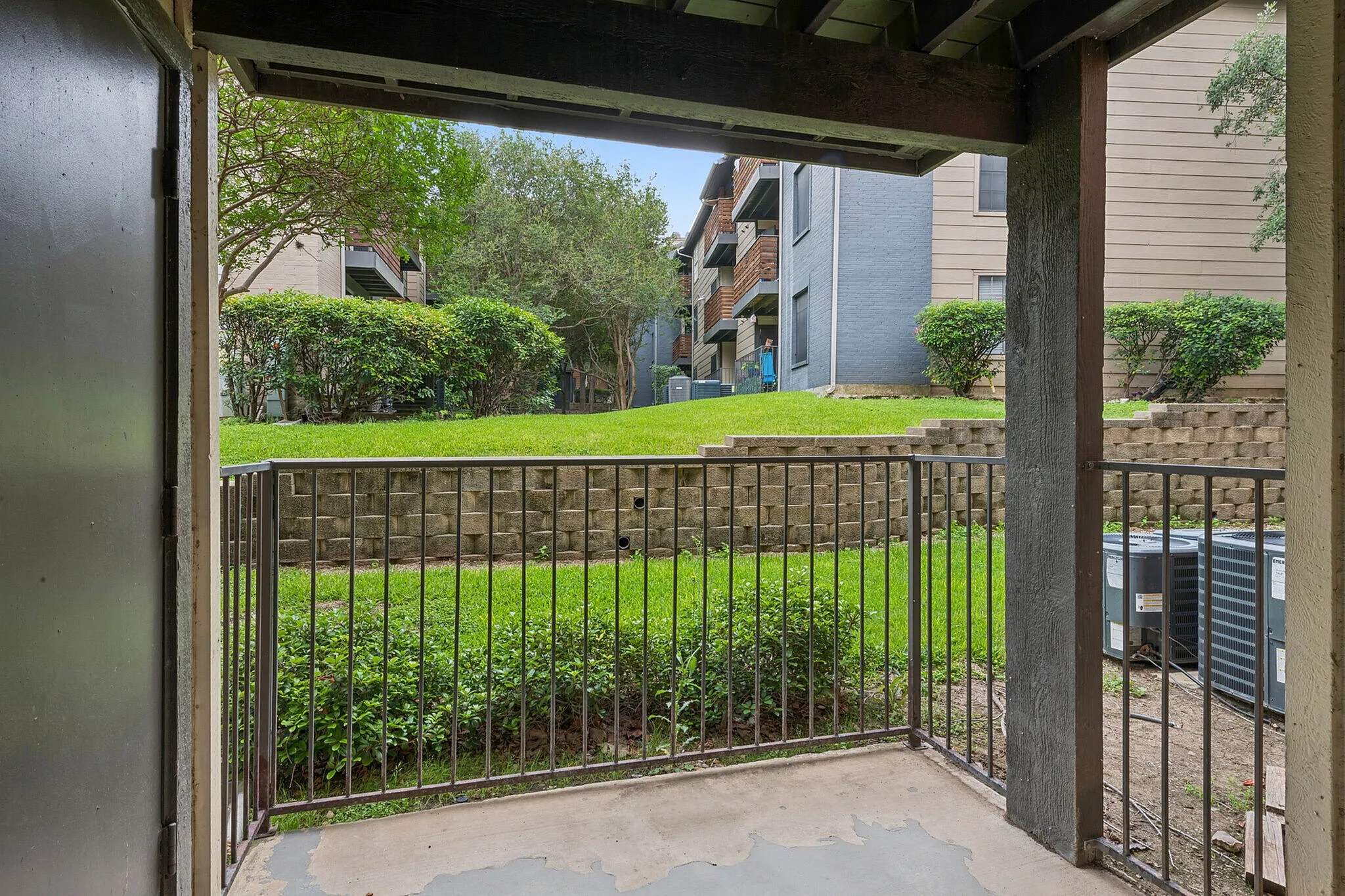 Cozy patio view overlooking vibrant green lawn and modern apartment buildings, ideal for relaxation.