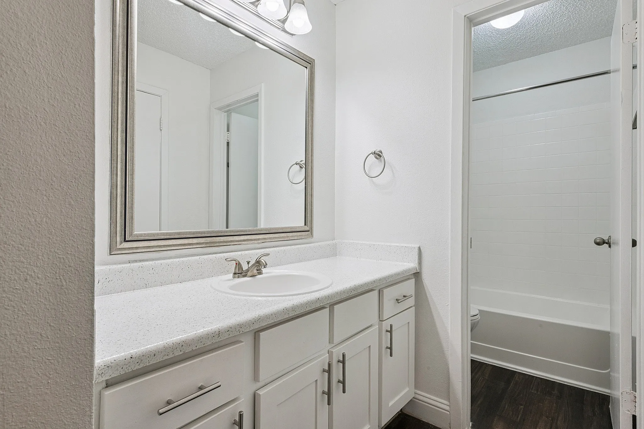 Elegant bathroom featuring modern vanity with sleek white cabinetry, a large framed mirror, and a pristine bathtub, highlighting luxurious design and functionality.