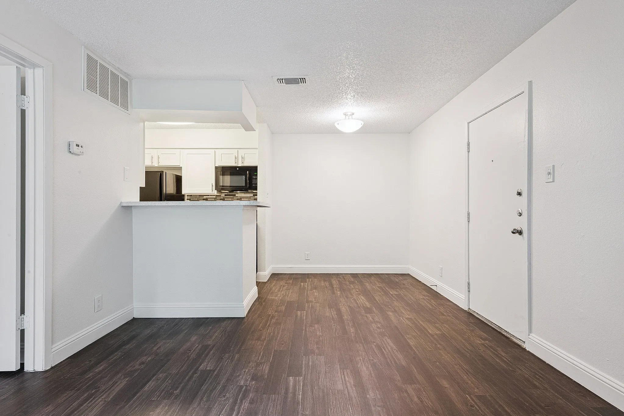 Sleek modern apartment interior featuring elegant hardwood floors, a stylish open kitchen with new appliances, and ample natural lighting.