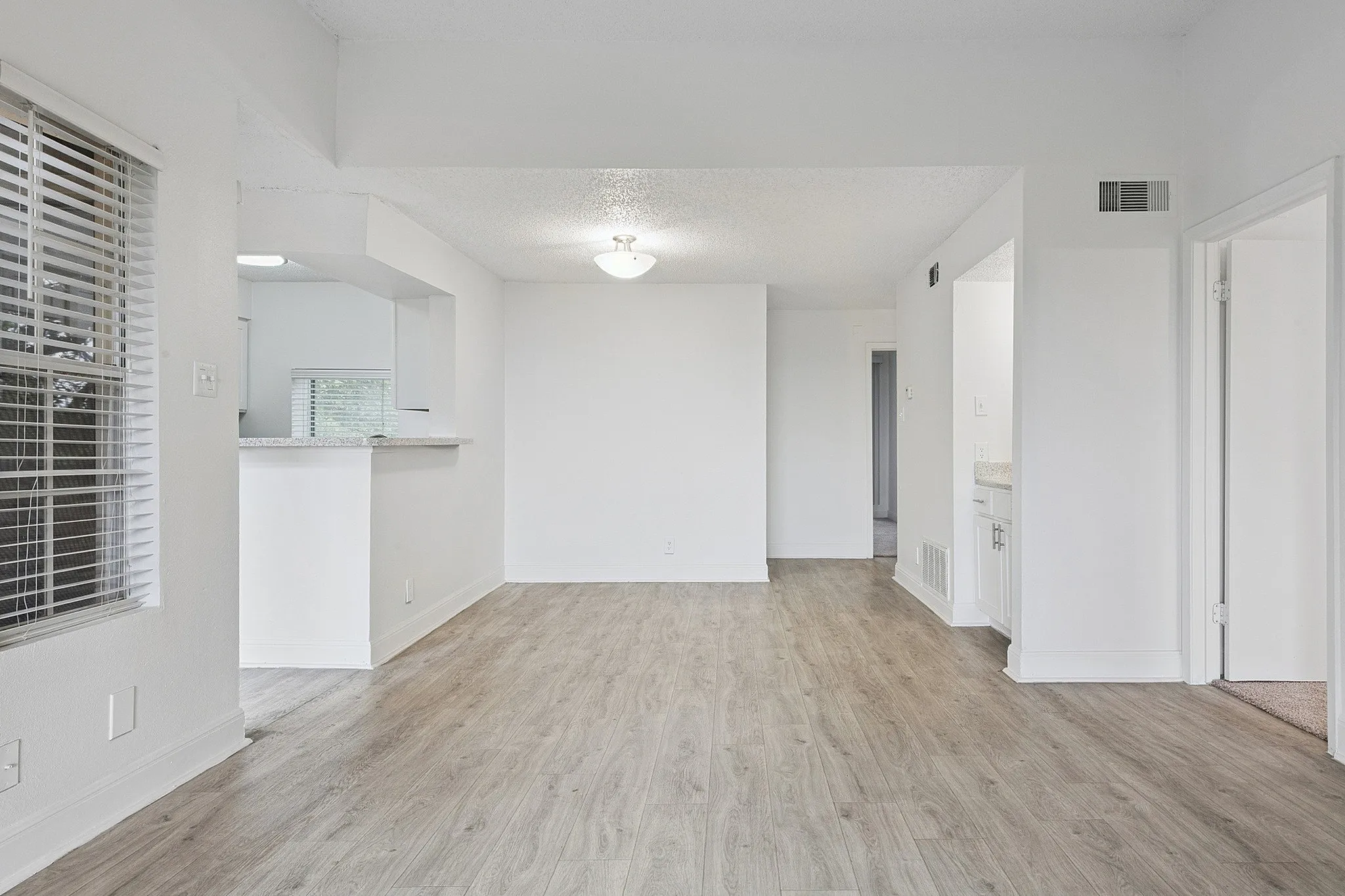 Bright and open living space with sleek hardwood floors and modern kitchen view, perfect for contemporary living.