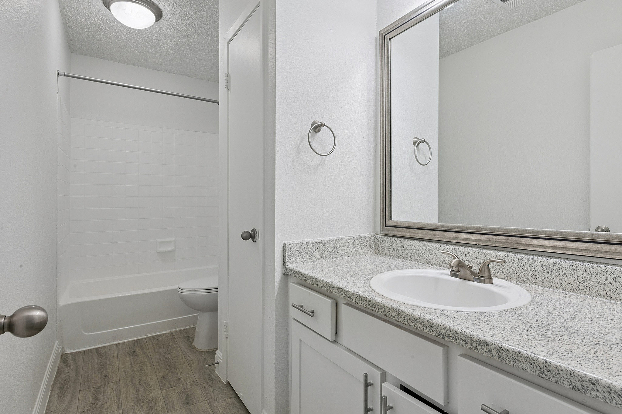 Modern bathroom featuring sleek granite countertops, large mirror, and elegant tile flooring.