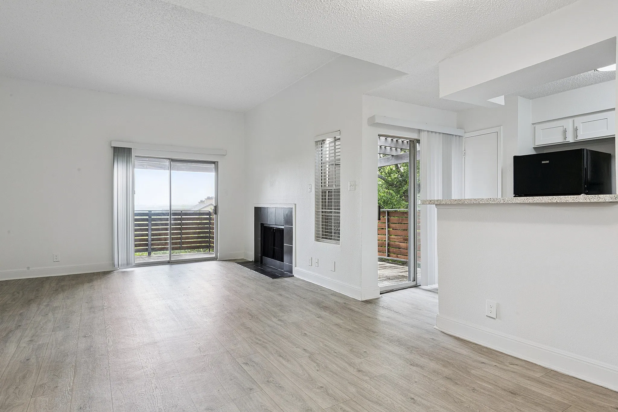 Bright and airy living space with hardwood floors, a cozy fireplace, and large sliding doors opening to a private balcony with scenic views.