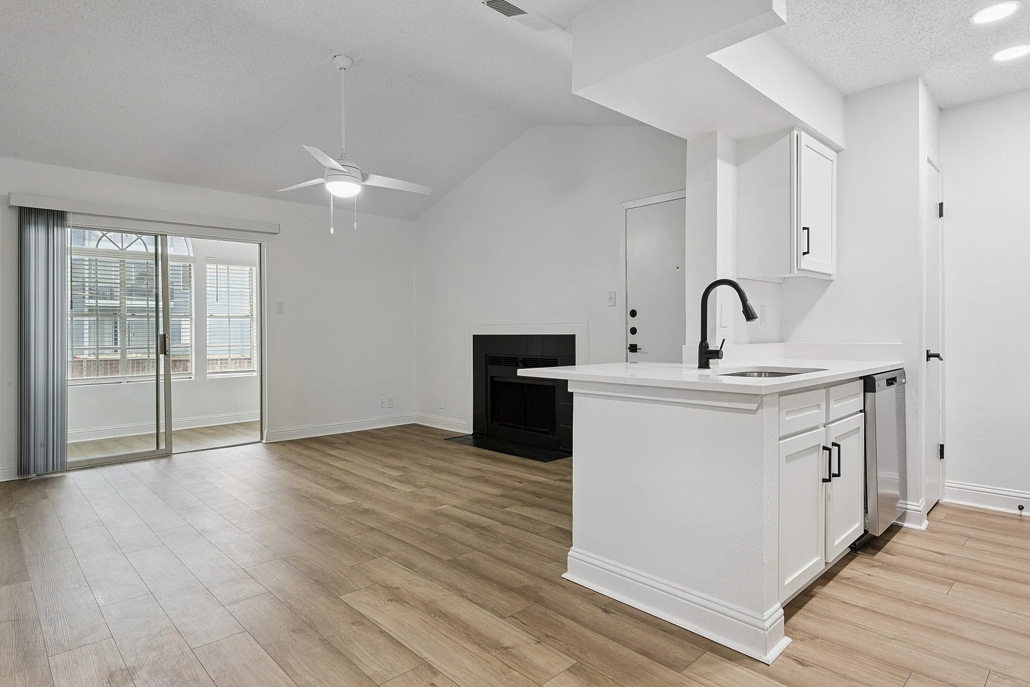Stylish modern apartment with open-concept layout, featuring sleek kitchen, cozy fireplace, and elegant hardwood floors, complemented by abundant natural light.
