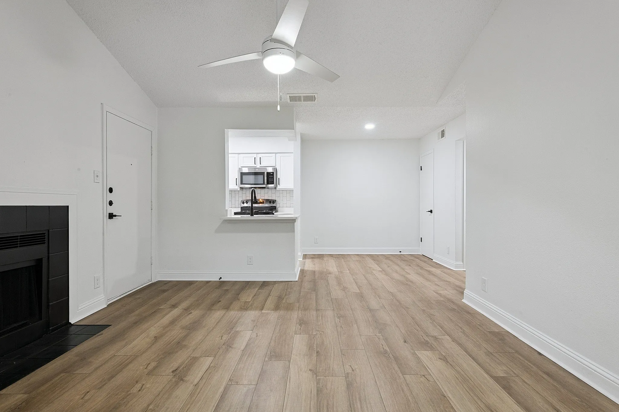 Modern apartment interior featuring sleek wood flooring, a cozy fireplace, and a stylish kitchen with stainless steel appliances.