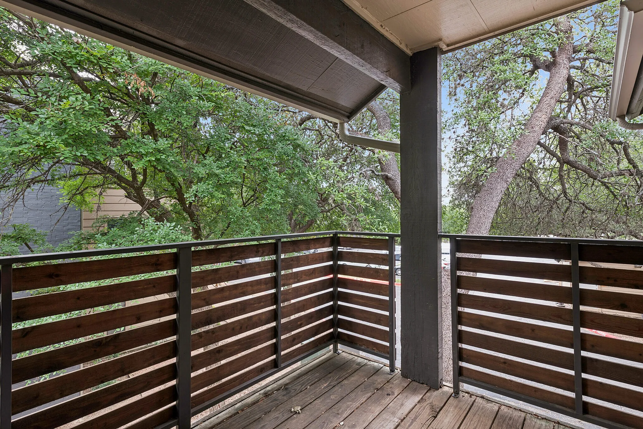 Inviting balcony with wooden railing surrounded by lush greenery, perfect for relaxation and outdoor enjoyment.