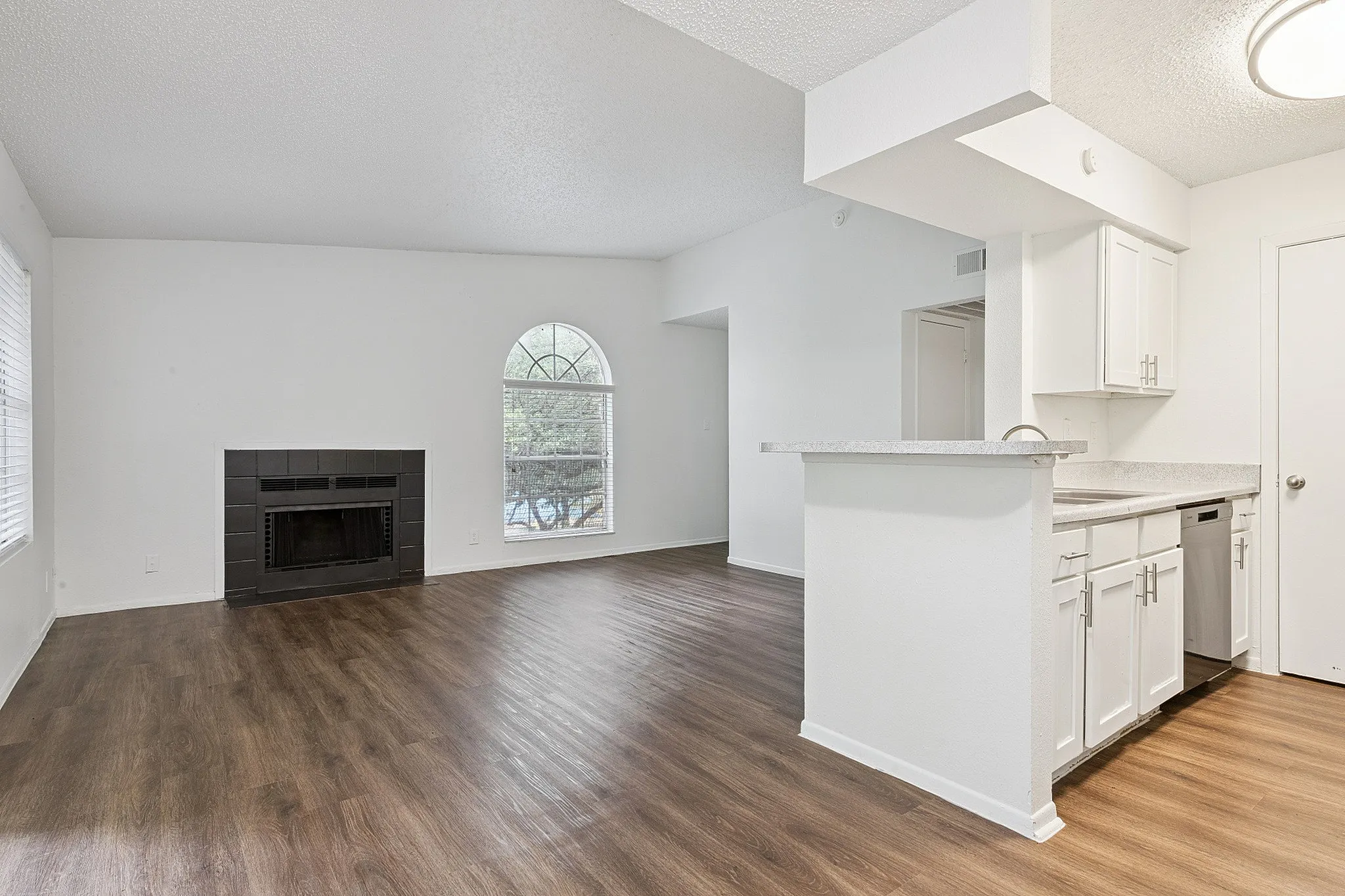 Chic and inviting open-plan apartment with elegant hardwood floors, modern kitchen, and a cozy fireplace.