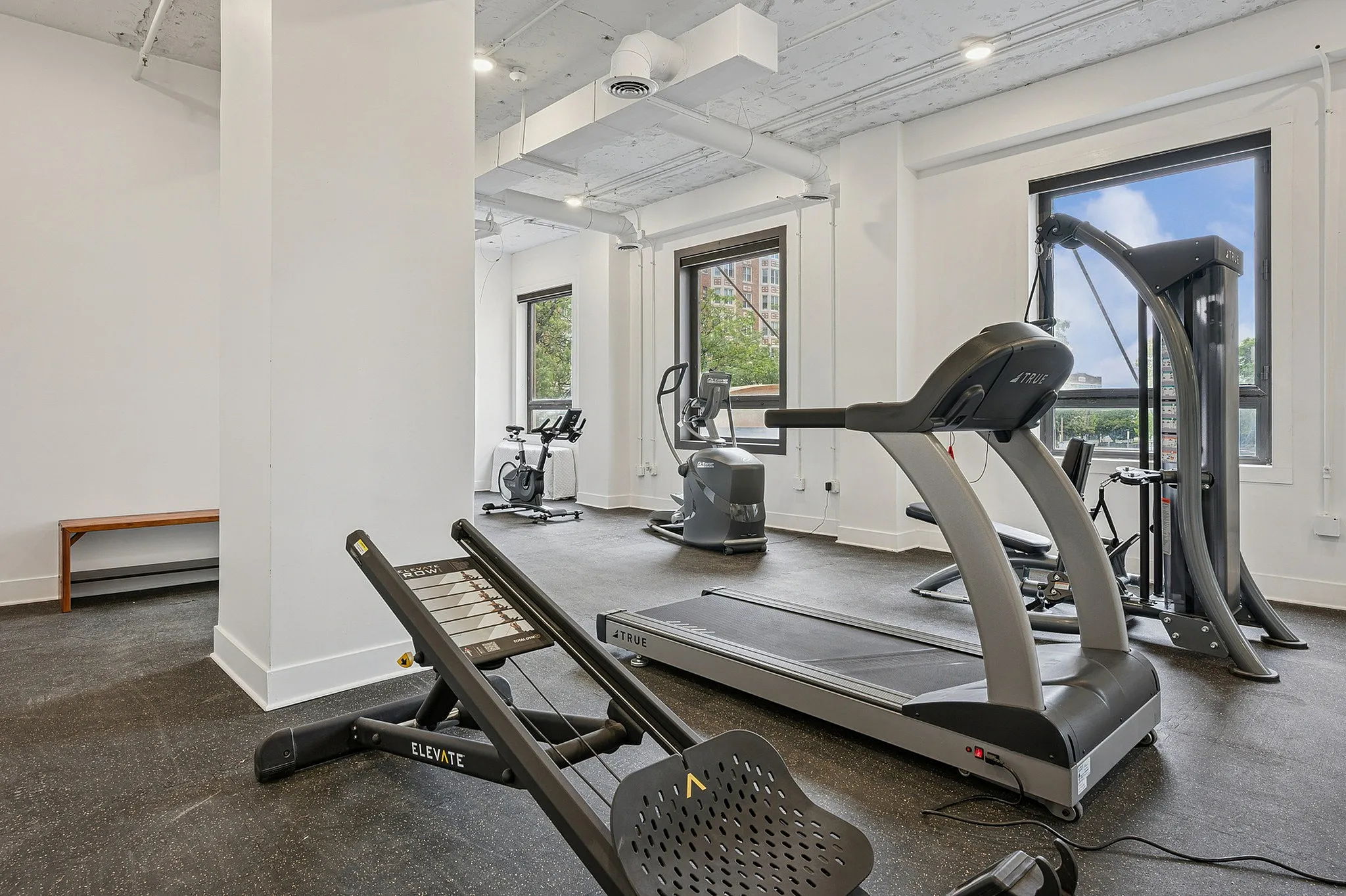 Bright and modern fitness center with state-of-the-art equipment, including a treadmill, stationary bike, and weight training machines.