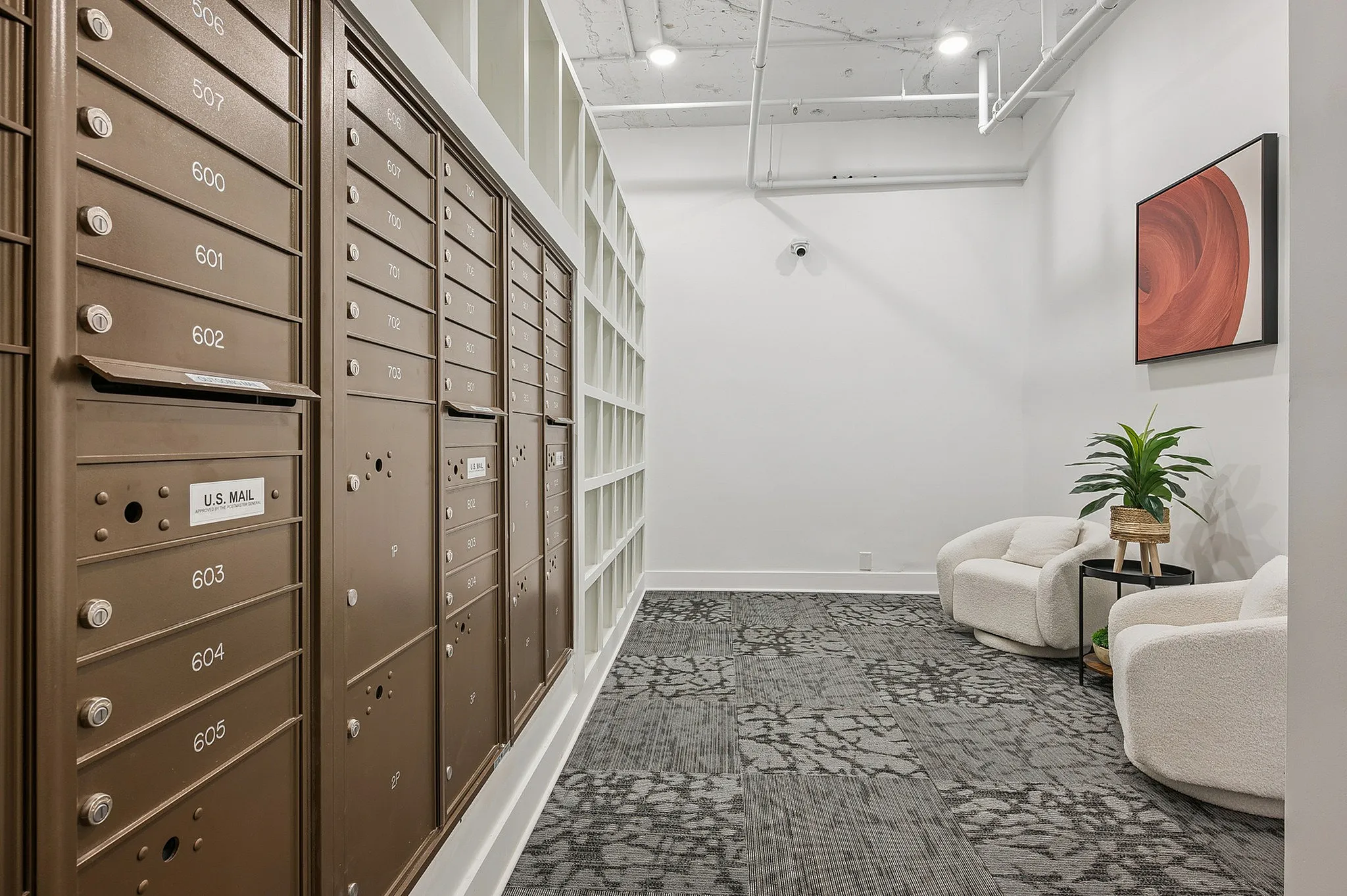 Chic apartment lobby with modern mailboxes, plush seating area, and stylish decor.