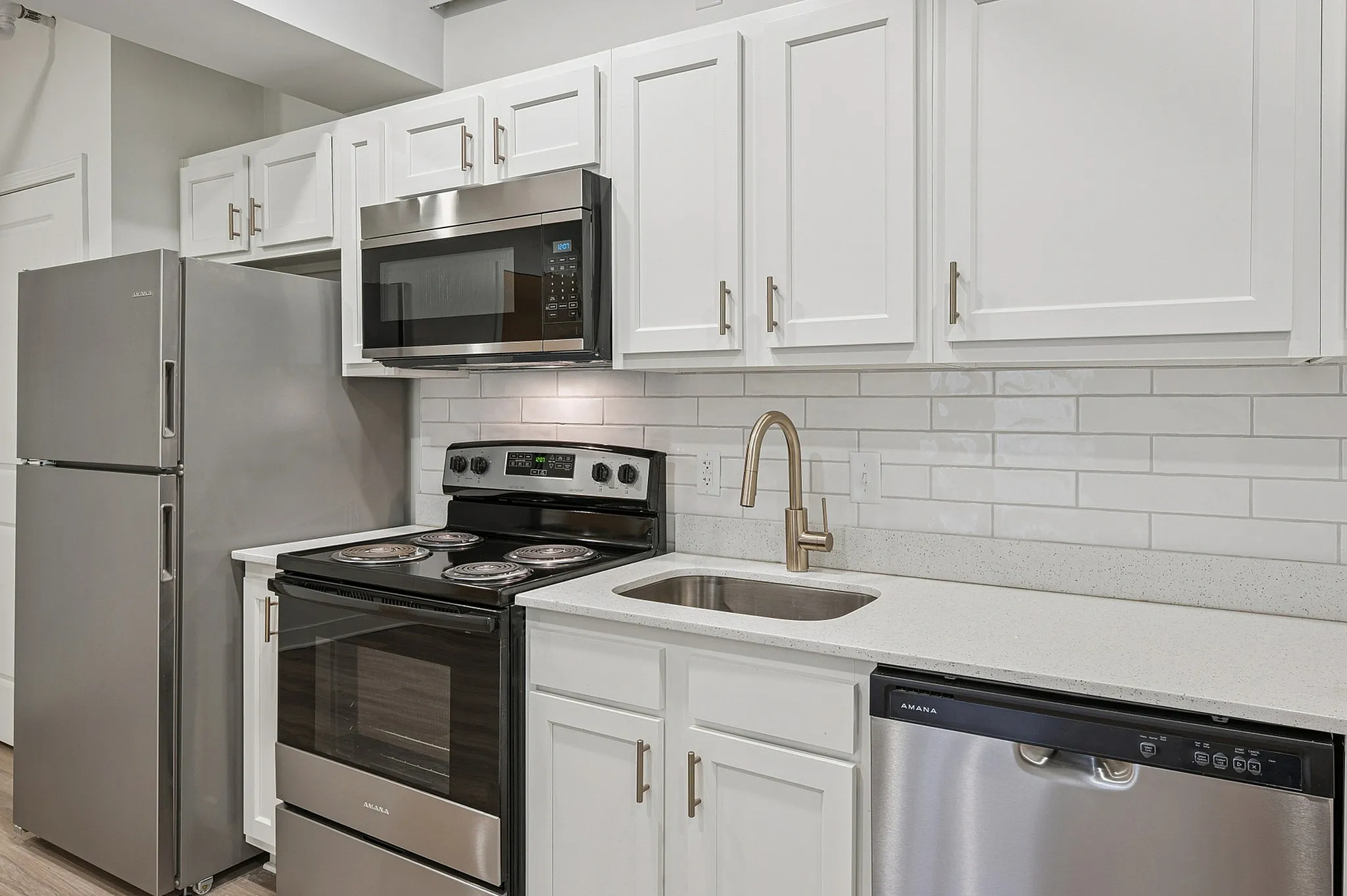Contemporary kitchen with sleek stainless steel appliances, pristine white cabinetry, and elegant subway tile backsplash.