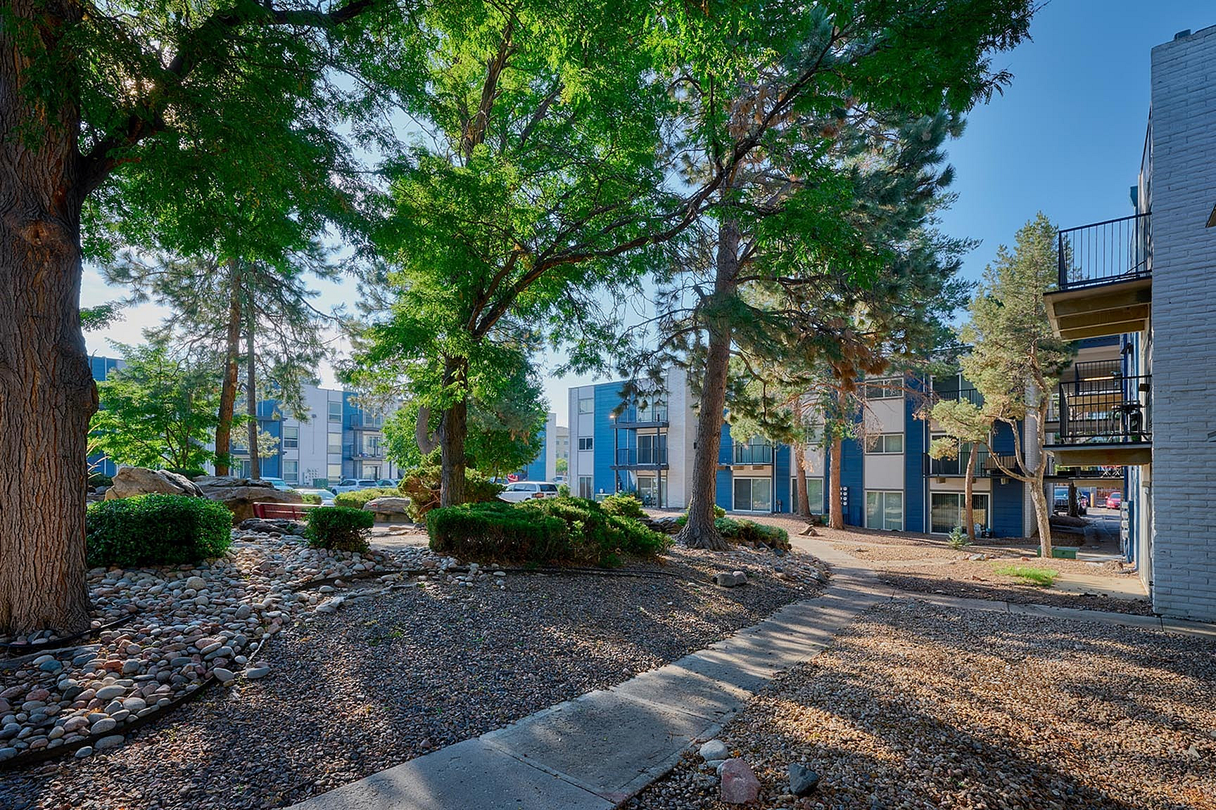 Scenic apartment complex with lush greenery and stone pathways in a serene natural setting.