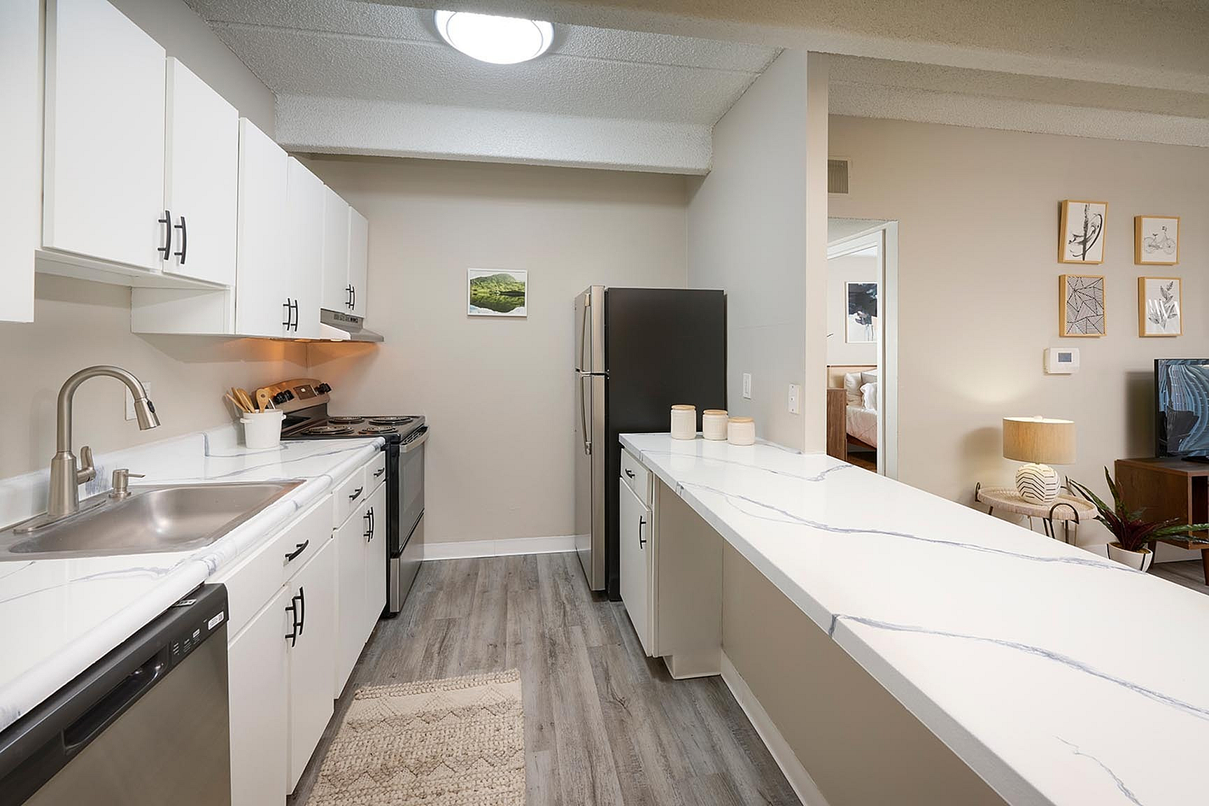 Contemporary kitchen with sleek white cabinets, marble counters, stainless steel appliances, and inviting open plan layout.