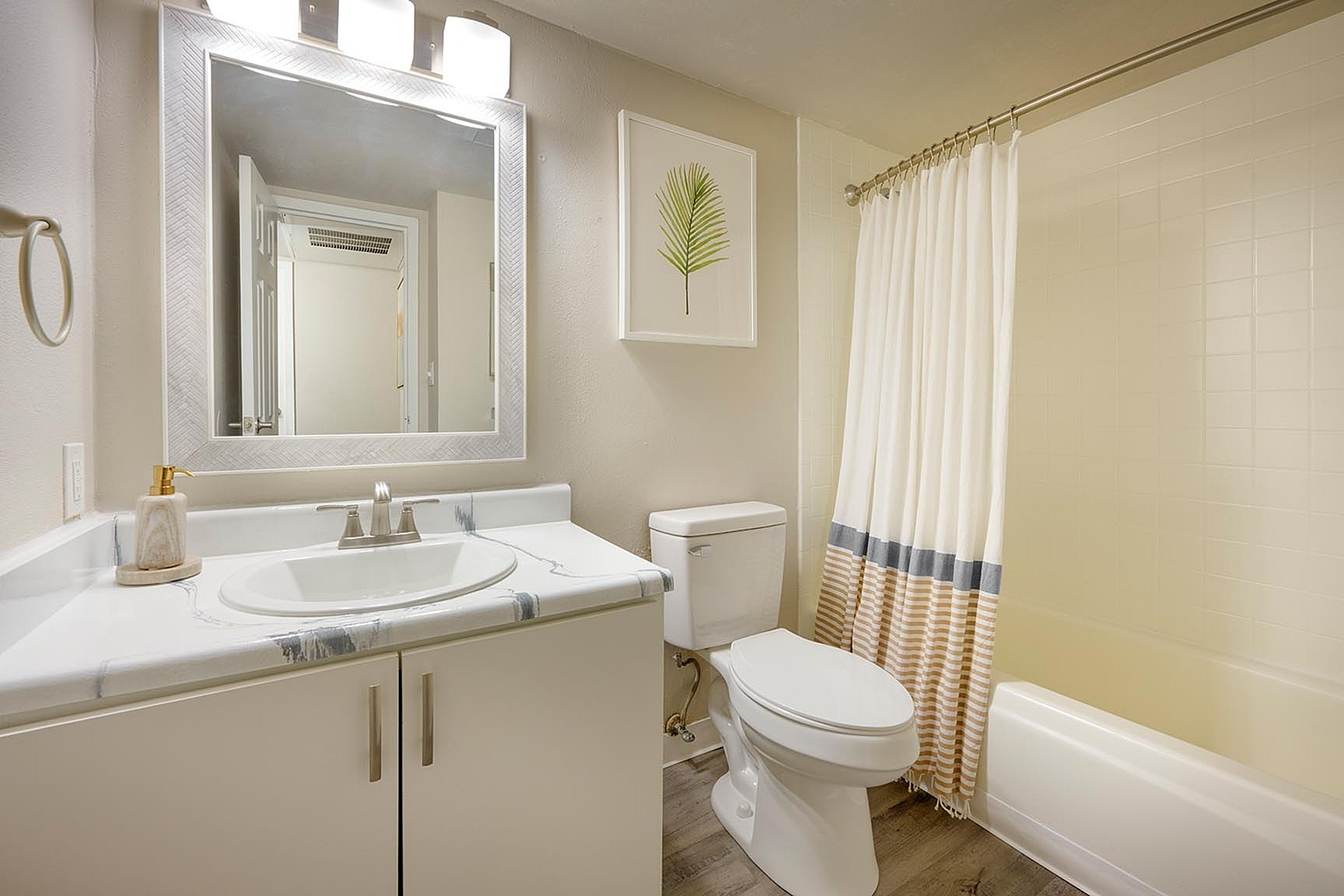 Elegant and modern bathroom featuring a stylish vanity with a marble countertop, a framed mirror, and a chic shower curtain for a sophisticated touch.