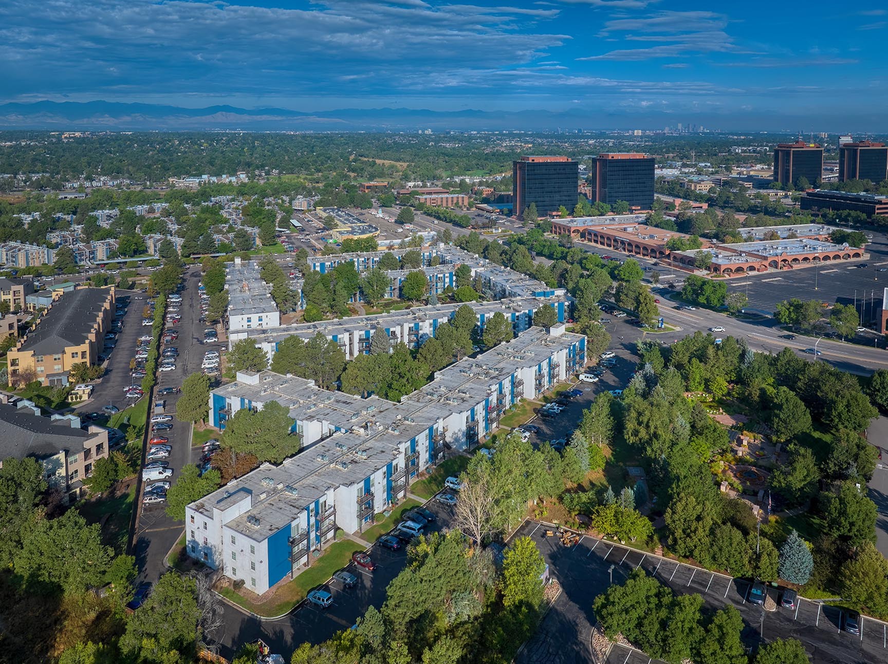 Breathtaking aerial view of a modern residential complex surrounded by lush greenery, showcasing vibrant apartments and nearby urban architecture.