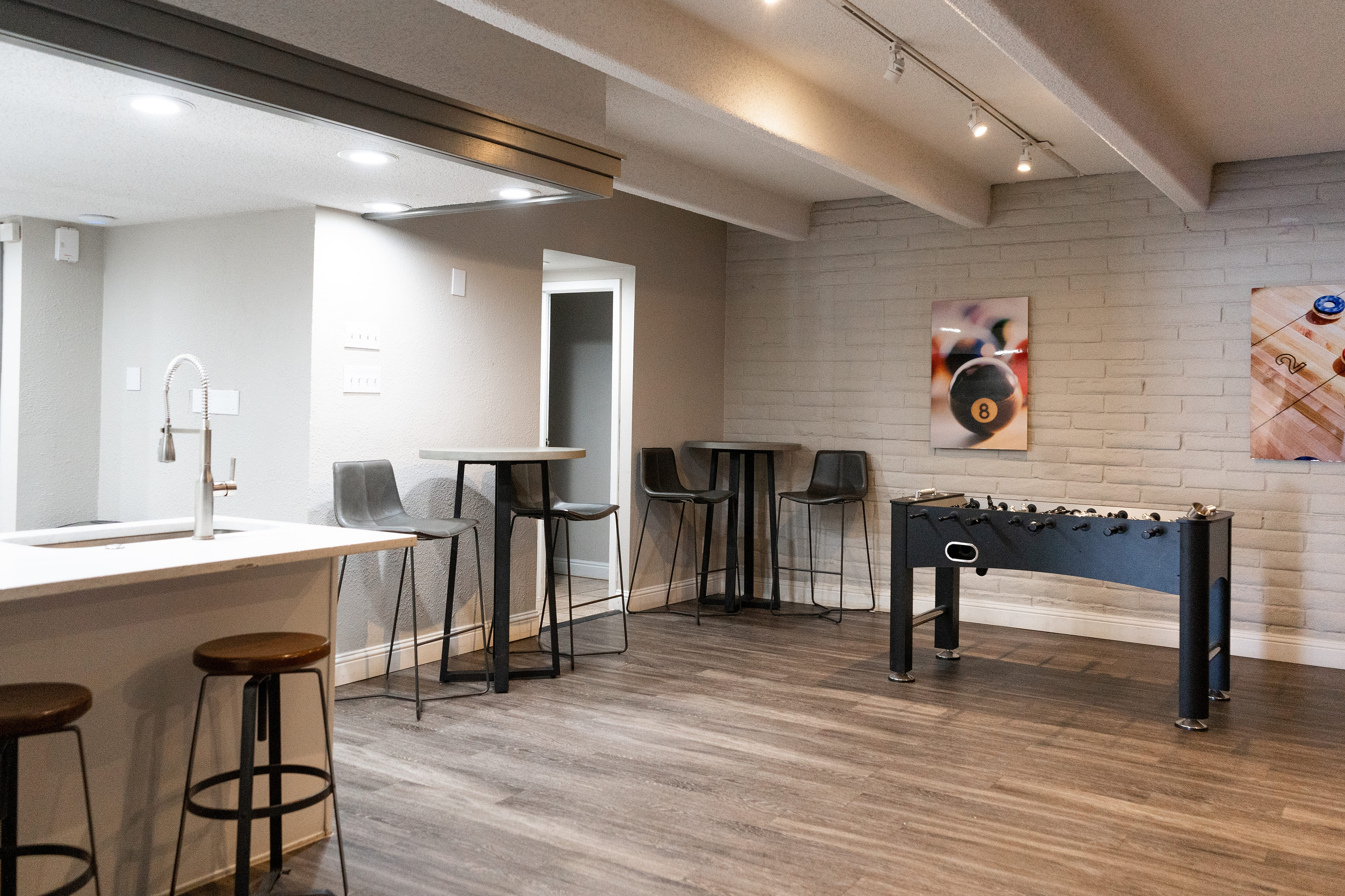 Modern game lounge with a sleek bar area, foosball table, and contemporary seating.