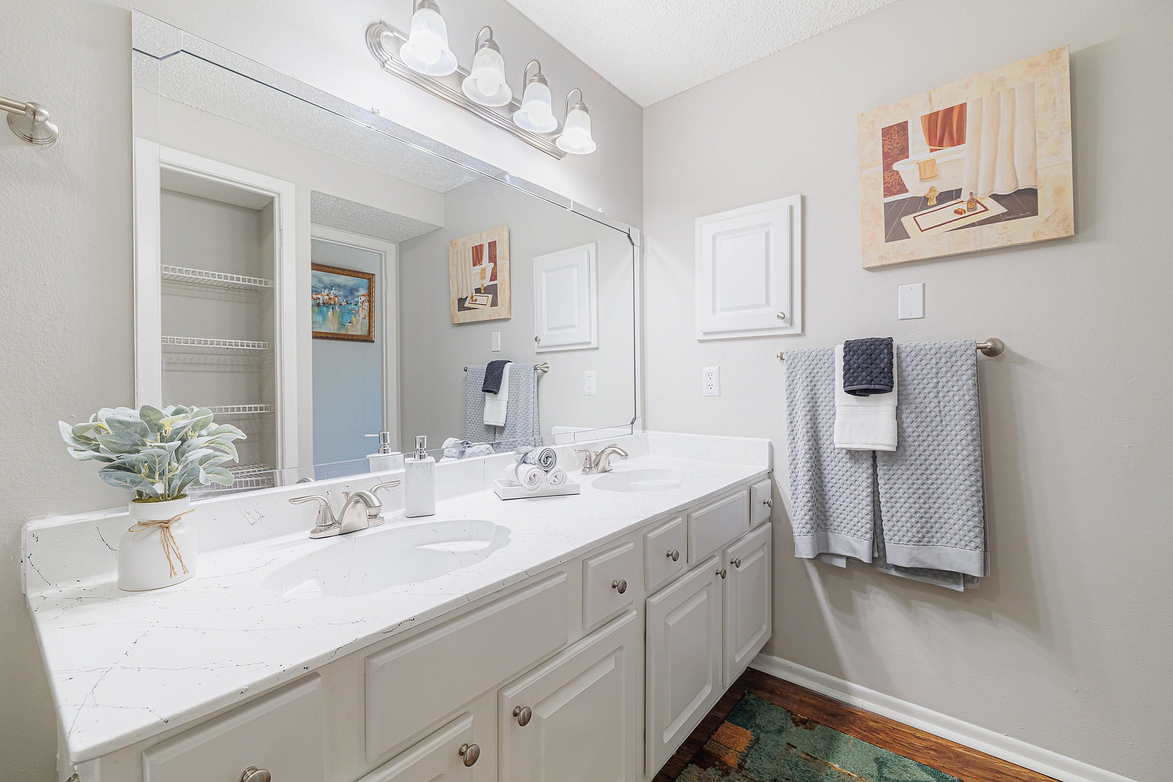 Bright, elegant bathroom featuring a double vanity with marble countertop, modern fixtures, and decorative wall art.