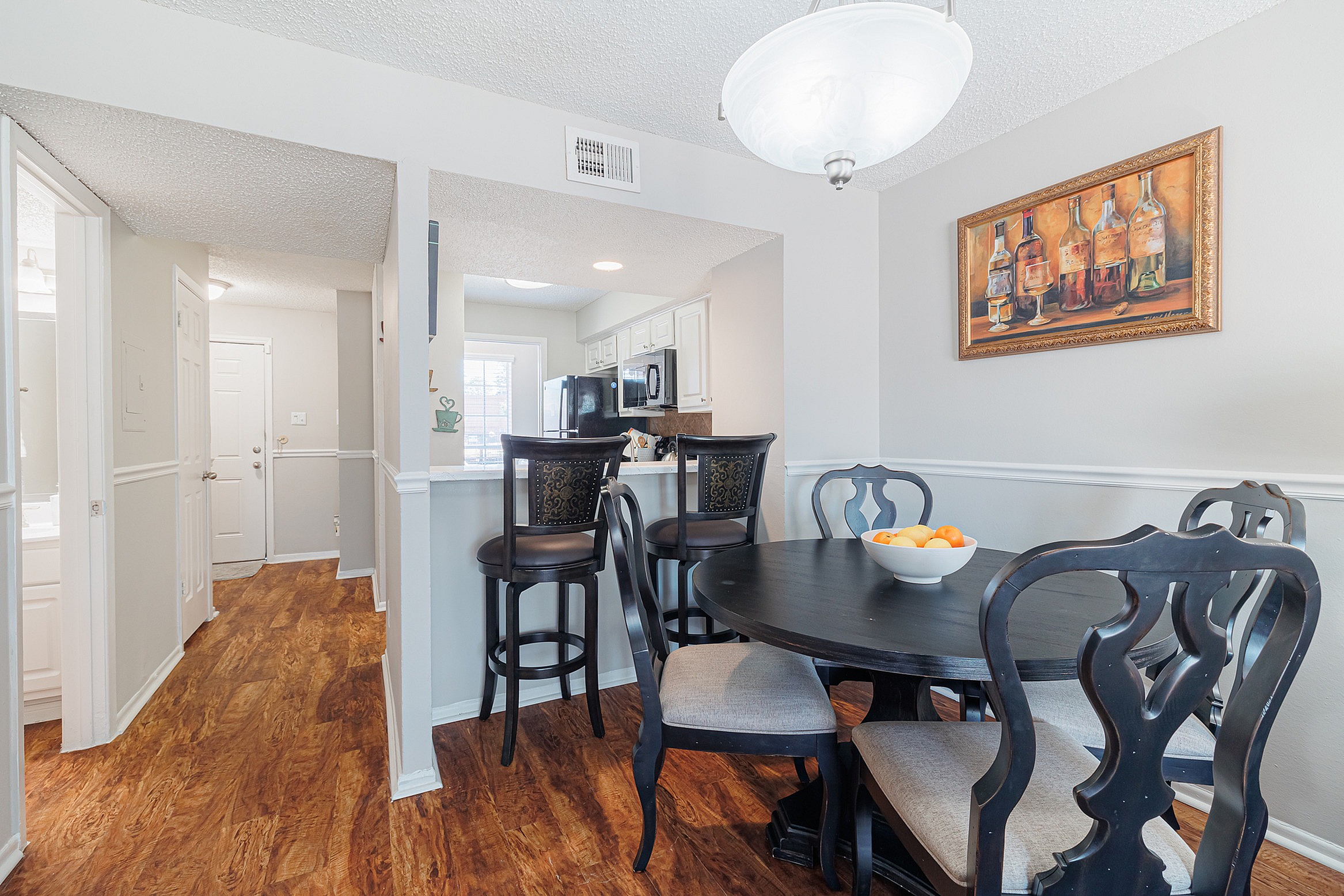 Inviting dining area with elegant dark wood furniture, open kitchen with bar seating, and rich wood flooring, perfect for gatherings.
