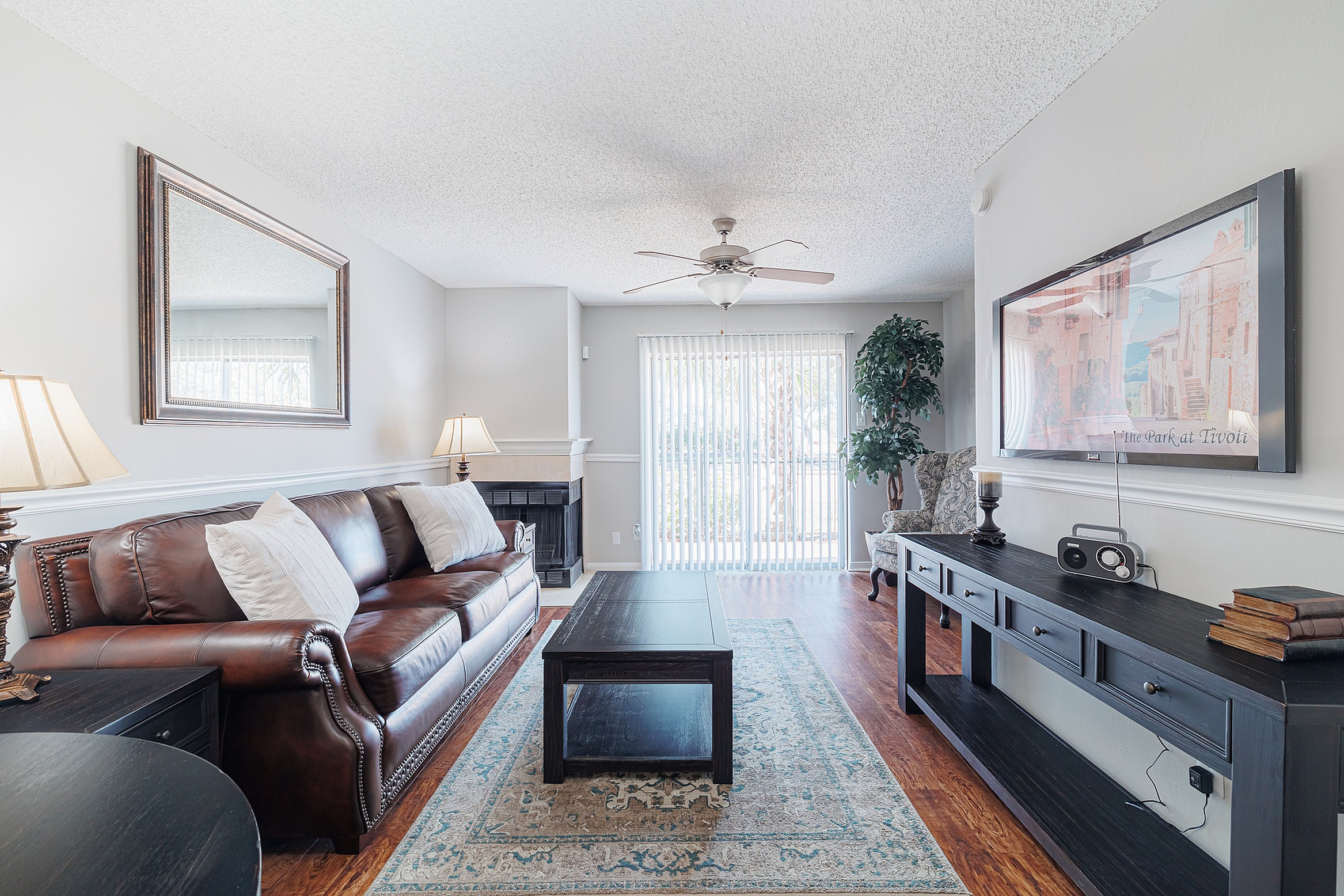 Inviting living room with a plush leather sofa, elegant decor, and large windows offering abundant natural light. Ideal for relaxation and entertaining.