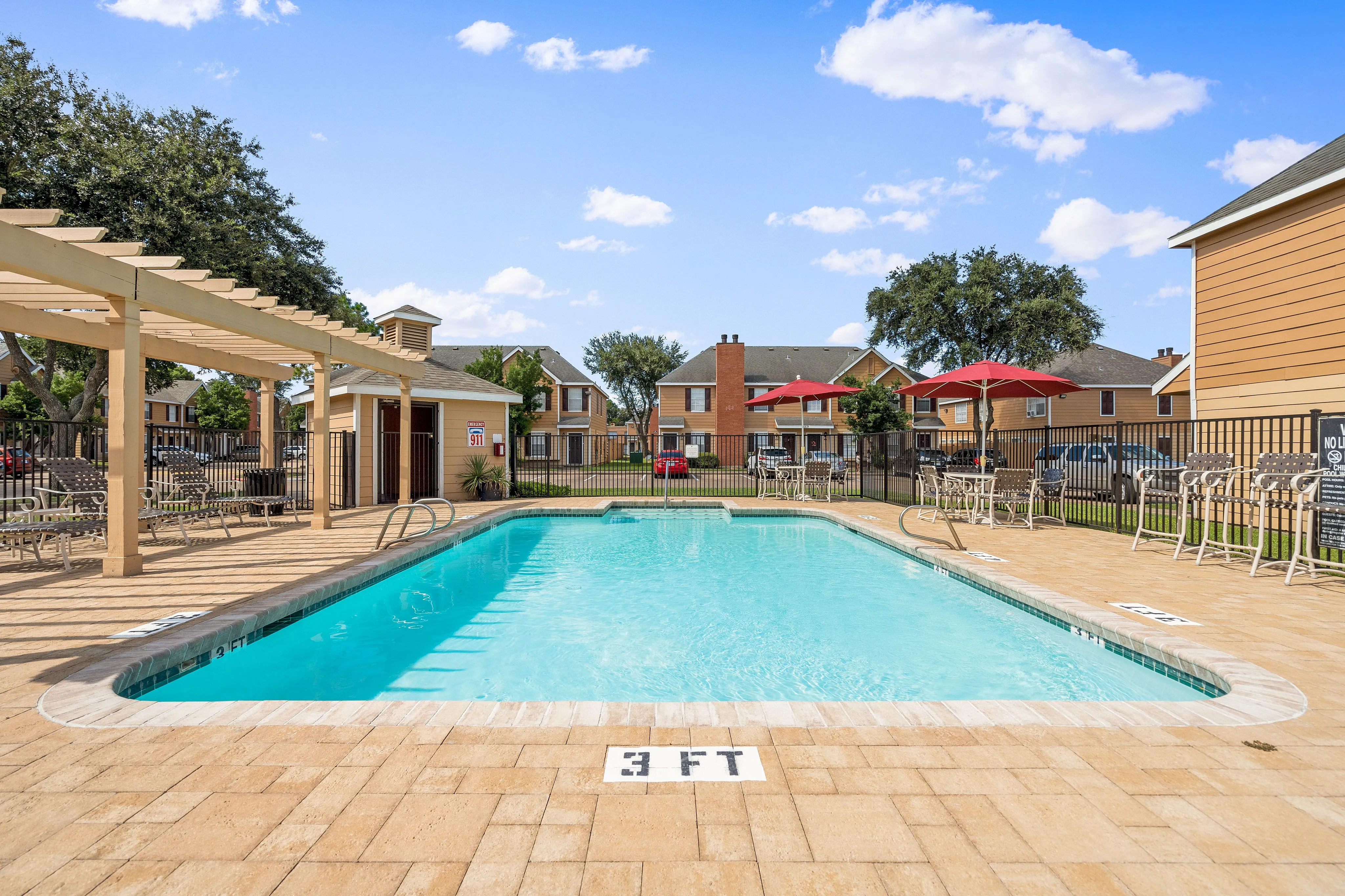 Inviting apartment community pool with sun loungers, pergola, and vibrant umbrellas, perfect for relaxation.