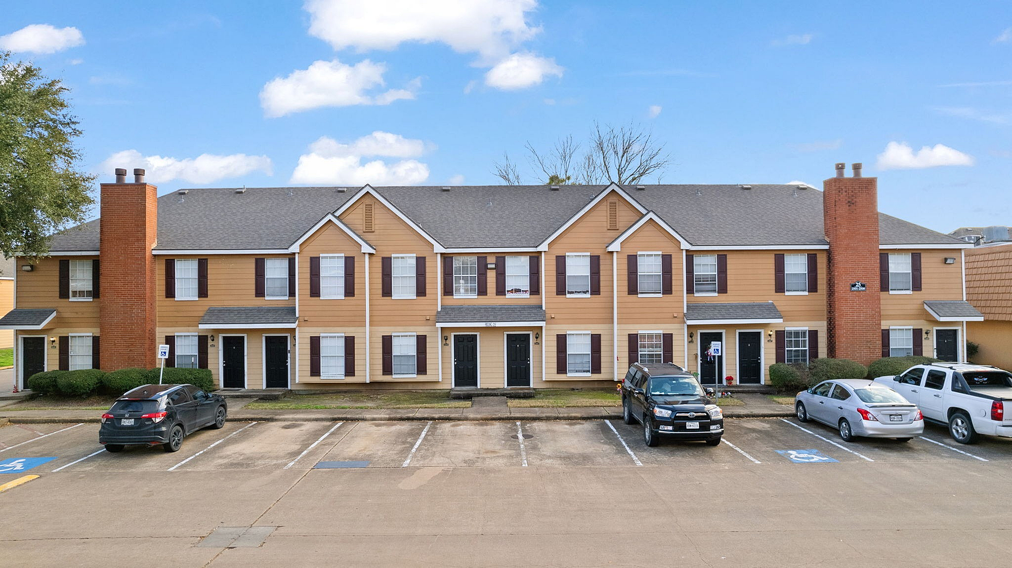 Charming townhouse complex with inviting brick accents, ample parking, and a serene suburban setting.
