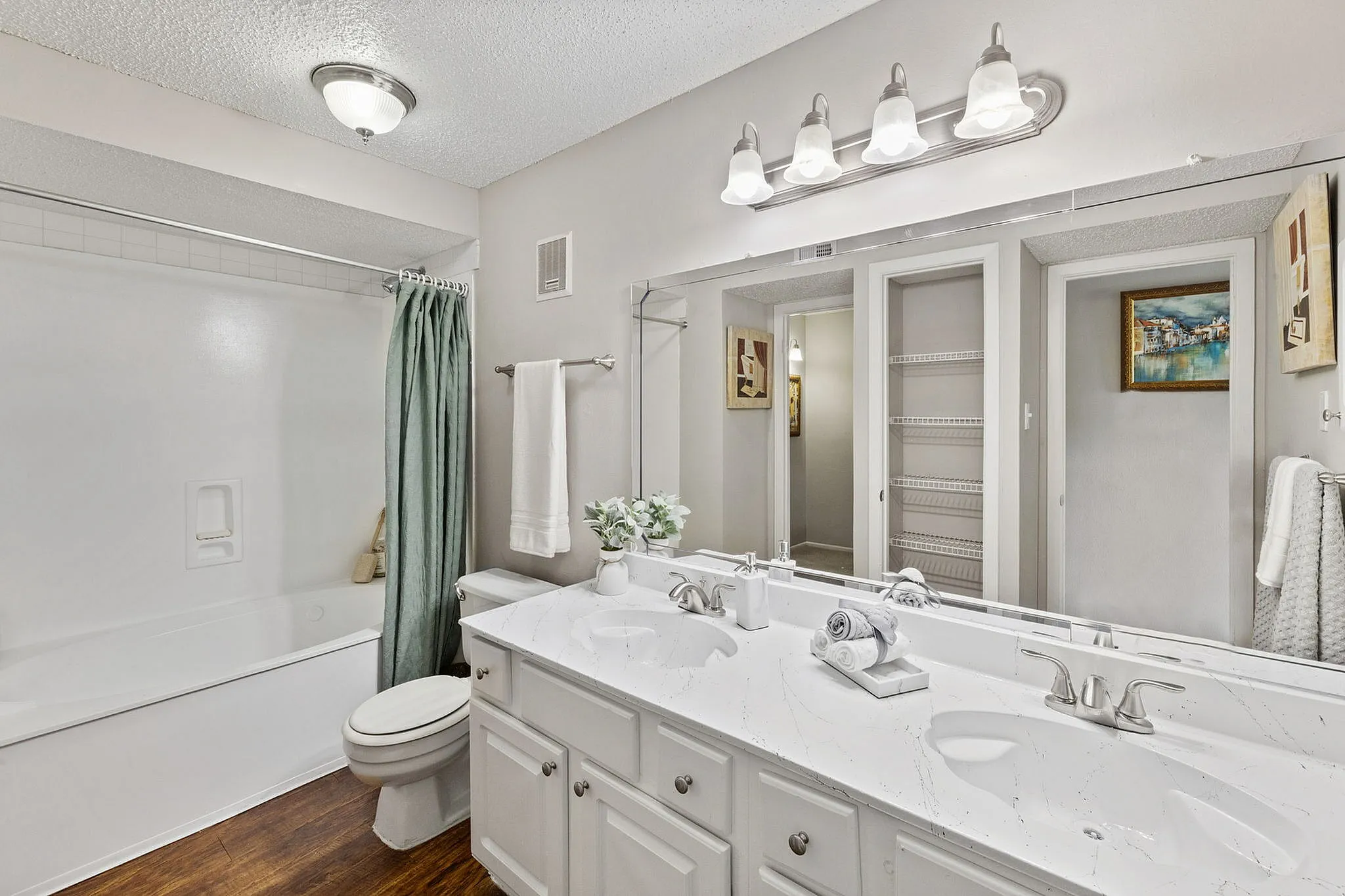 Elegant bathroom featuring a double vanity with marble countertops, ample storage, and a cozy bathtub with a stylish curtain.