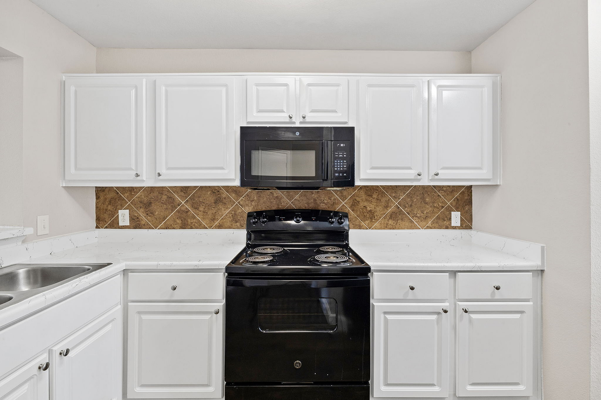 Modern kitchen featuring sleek white cabinetry, elegant marble countertops, and stylish black appliances.