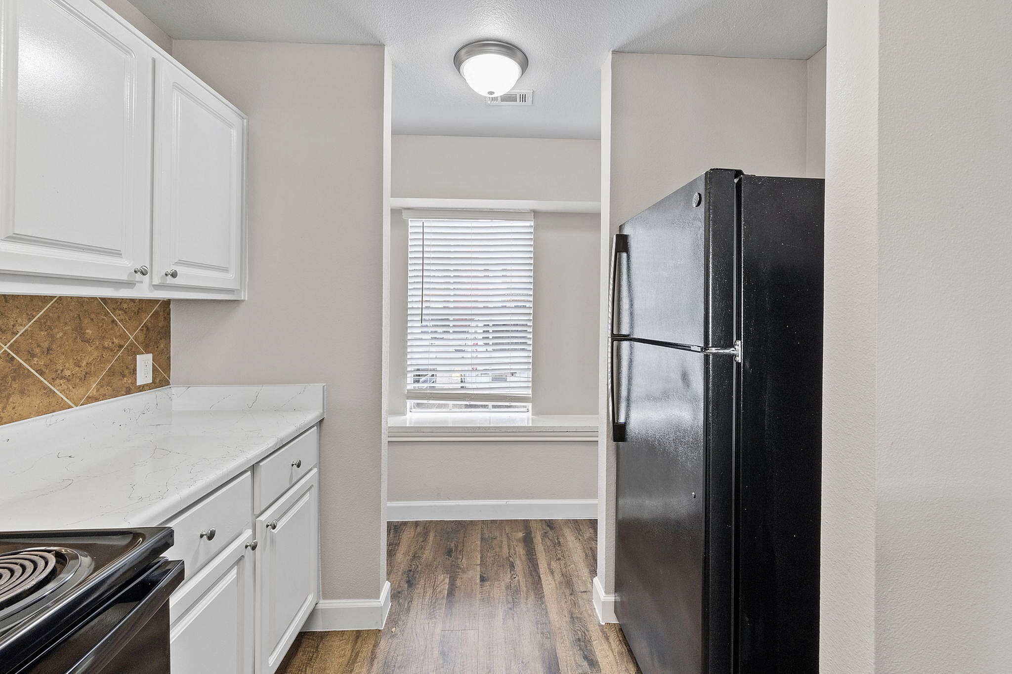 Modern kitchen with sleek black appliances, white cabinetry, and sunlit window for a bright, inviting space.