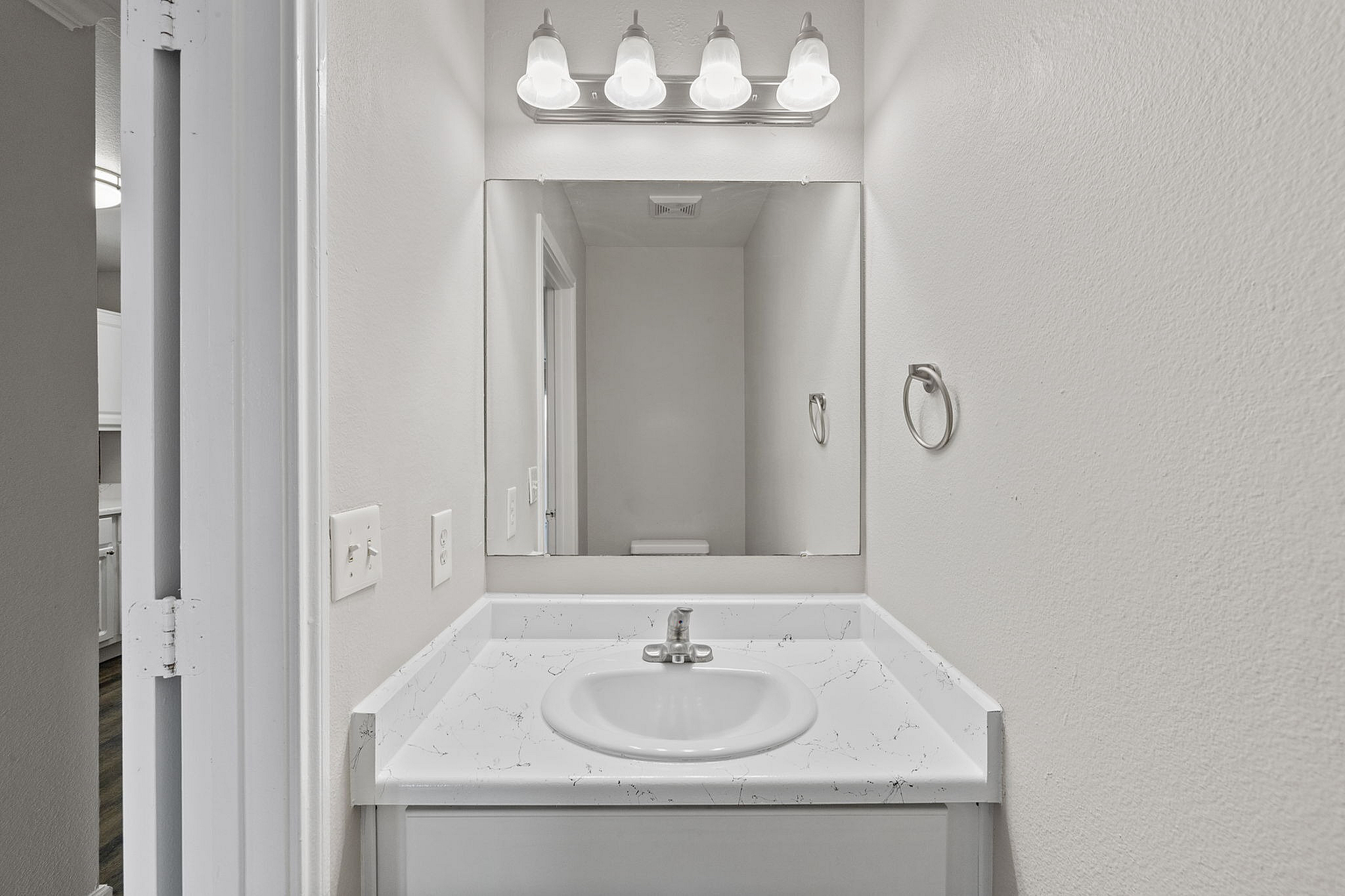 Elegant bathroom vanity with a sleek marble countertop, large mirror, and modern lighting fixture.