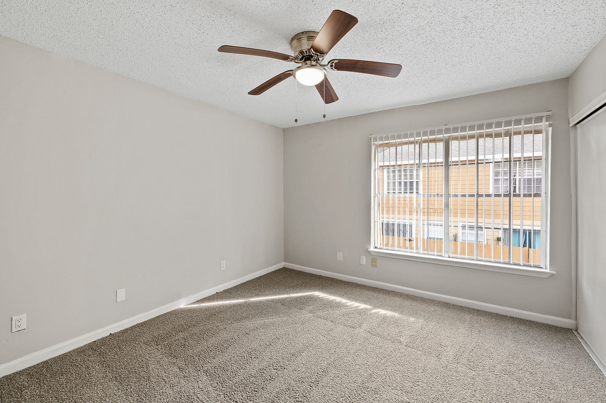Bright and spacious bedroom with plush carpet, a modern ceiling fan, and large window inviting ample natural light.
