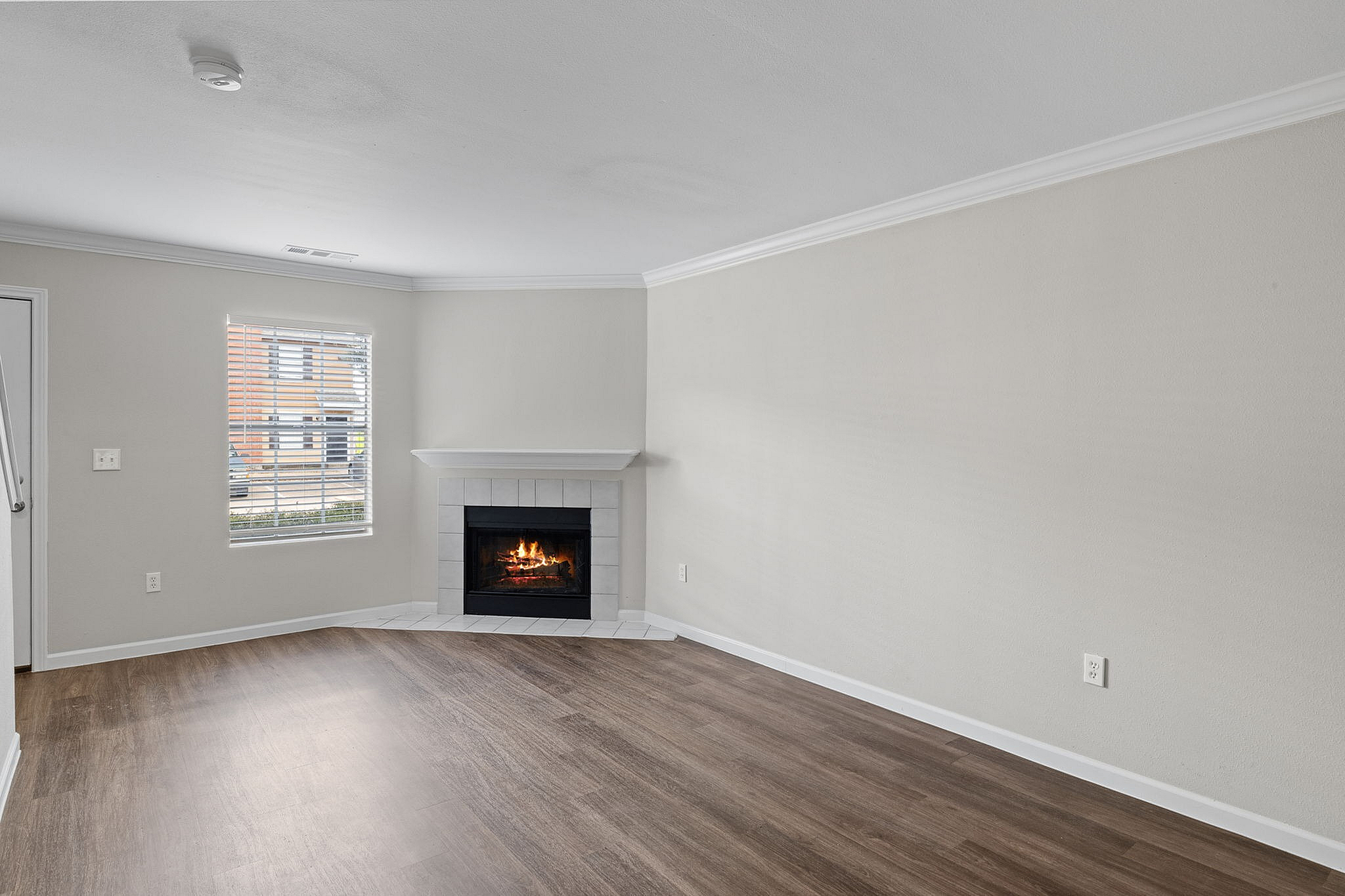 Inviting living room with elegant hardwood flooring, a cozy fireplace, and ample natural light through a large window.