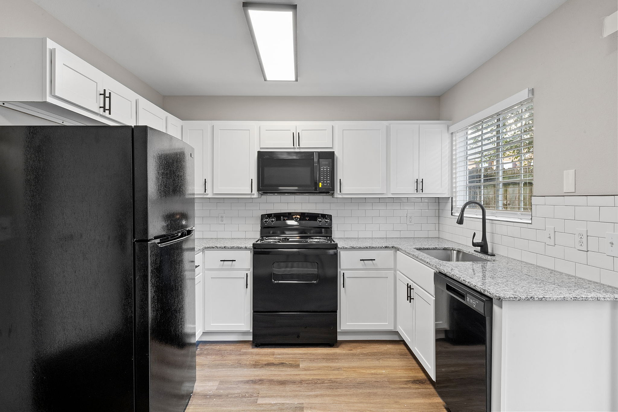 Modern kitchen with sleek black appliances, granite countertops, and stylish white cabinets for a contemporary feel.