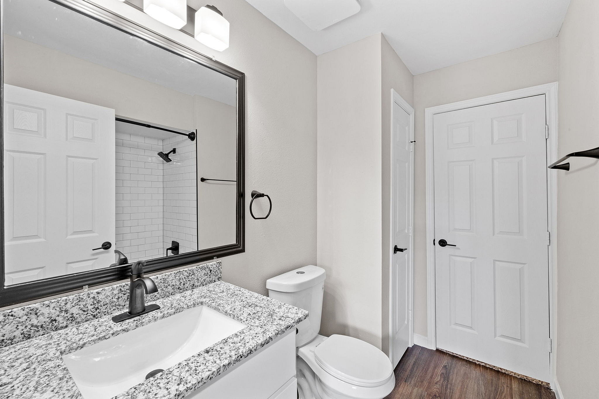 Sleek modern bathroom featuring a granite countertop, elegant fixtures, and a pristine shower with subway tiles.