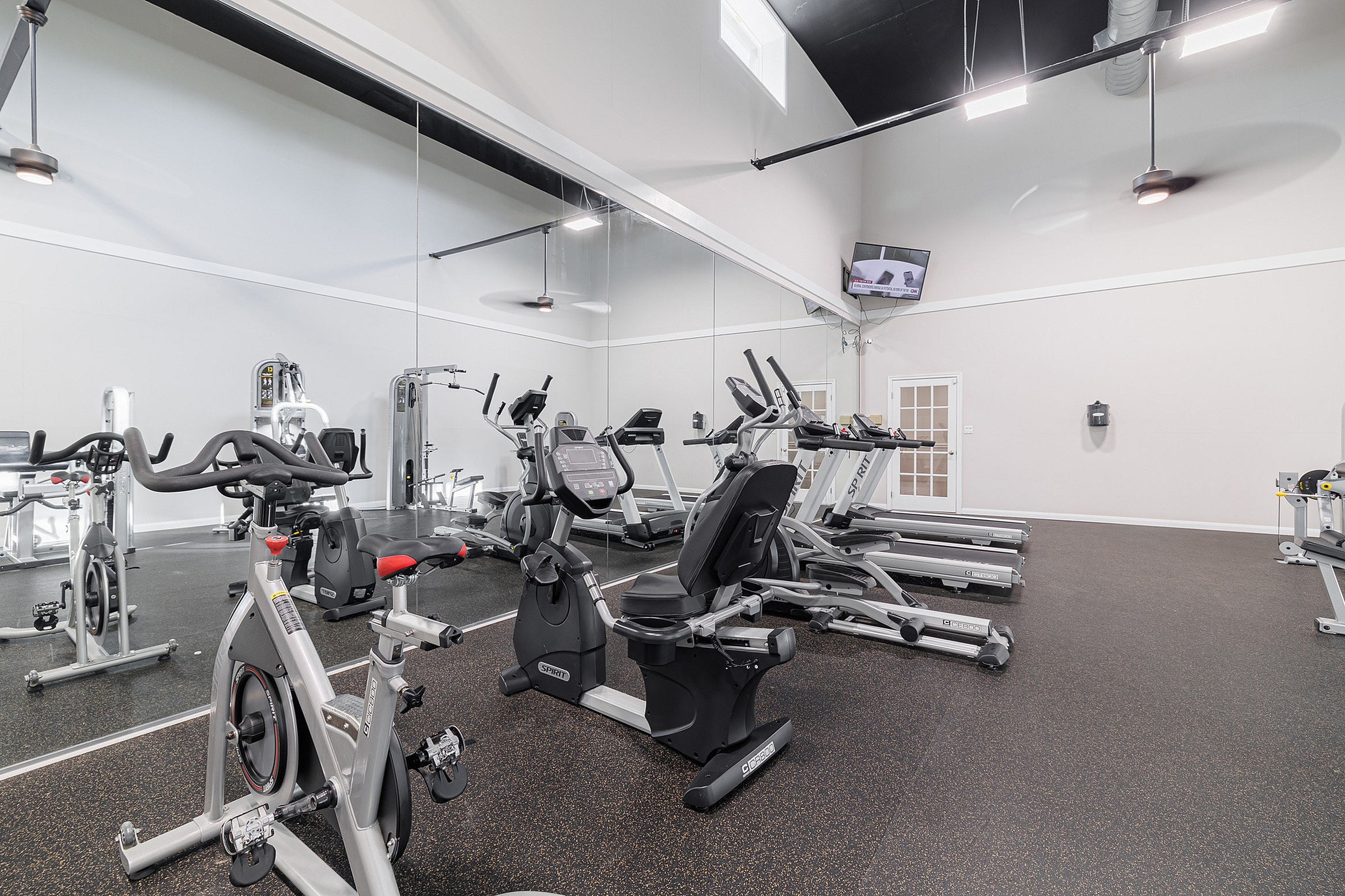 Modern fitness center featuring state-of-the-art exercise equipment, including treadmills and stationary bikes, with a sleek mirrored wall and bright lighting.