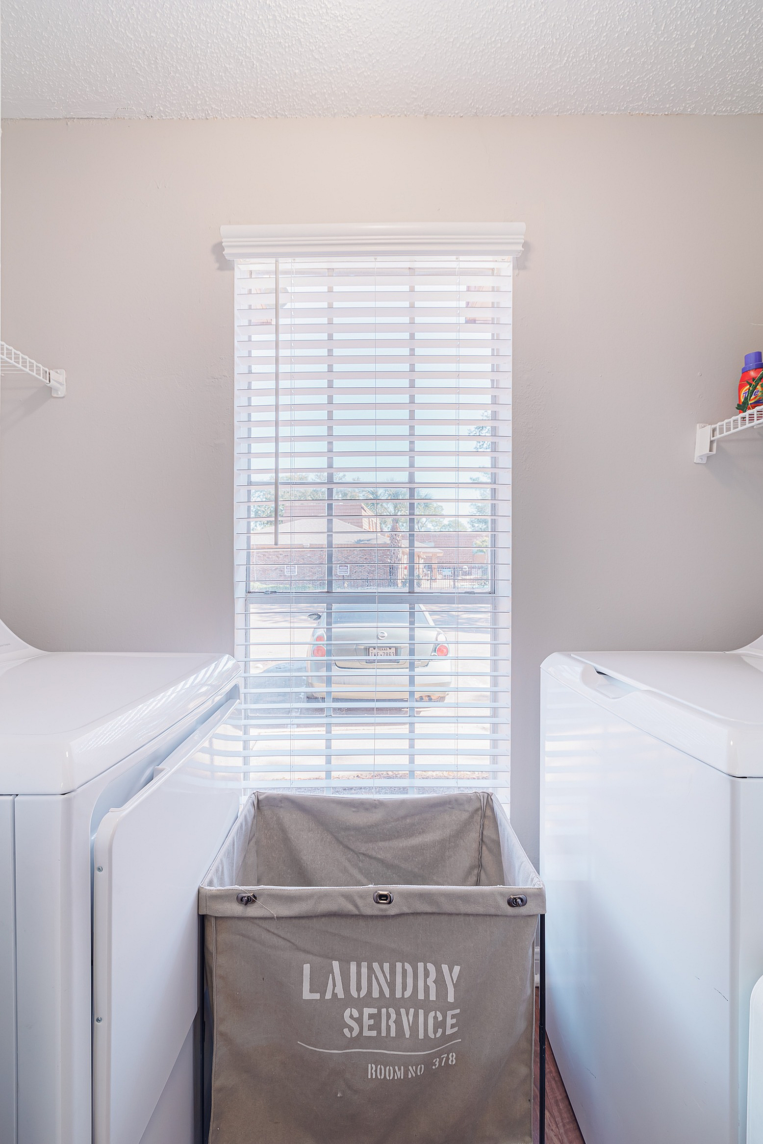 Bright, modern laundry room with large window, washing machine, and convenient shelving.