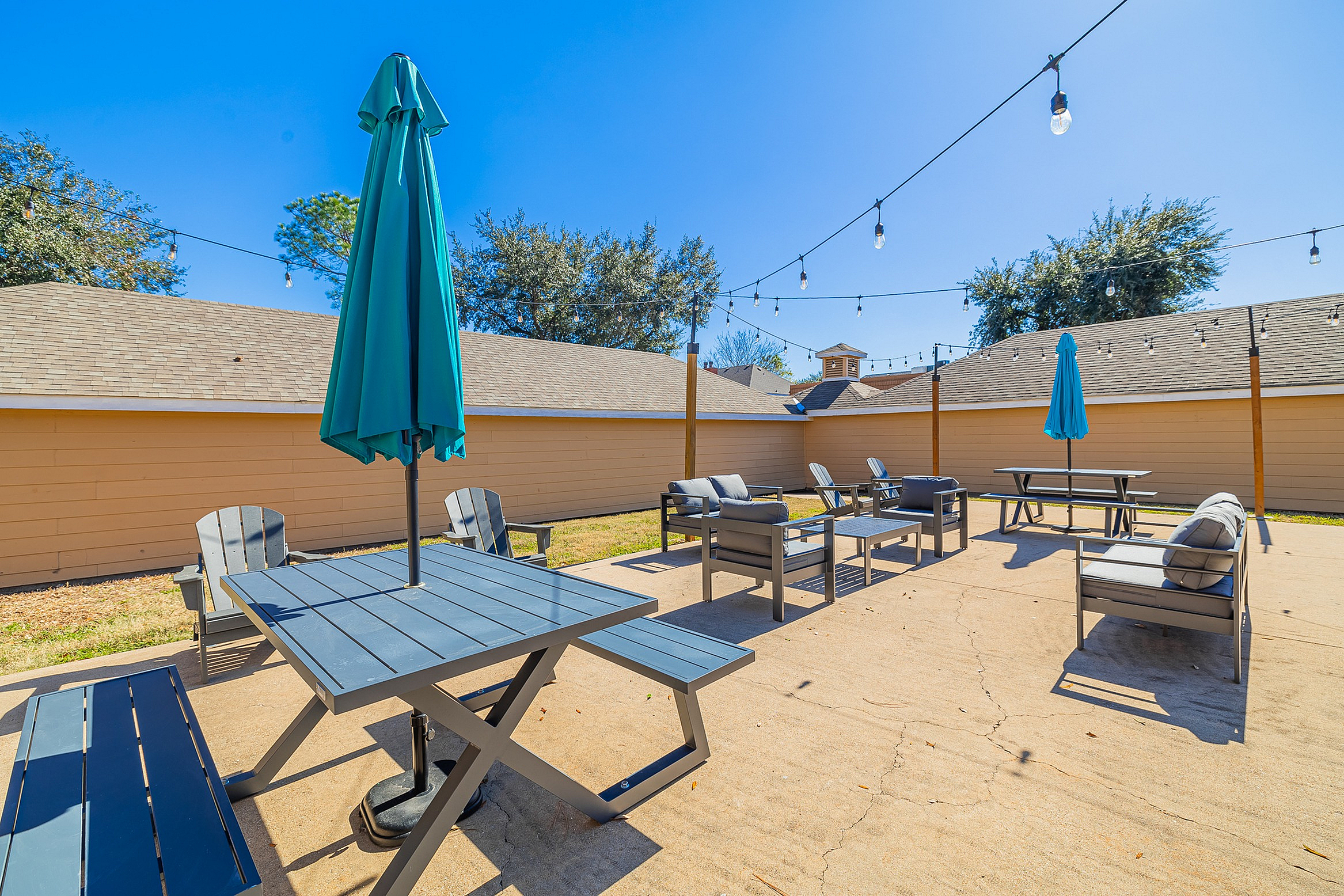 Inviting outdoor patio with cozy seating, shaded tables, and charming string lights, perfect for entertaining and relaxation.