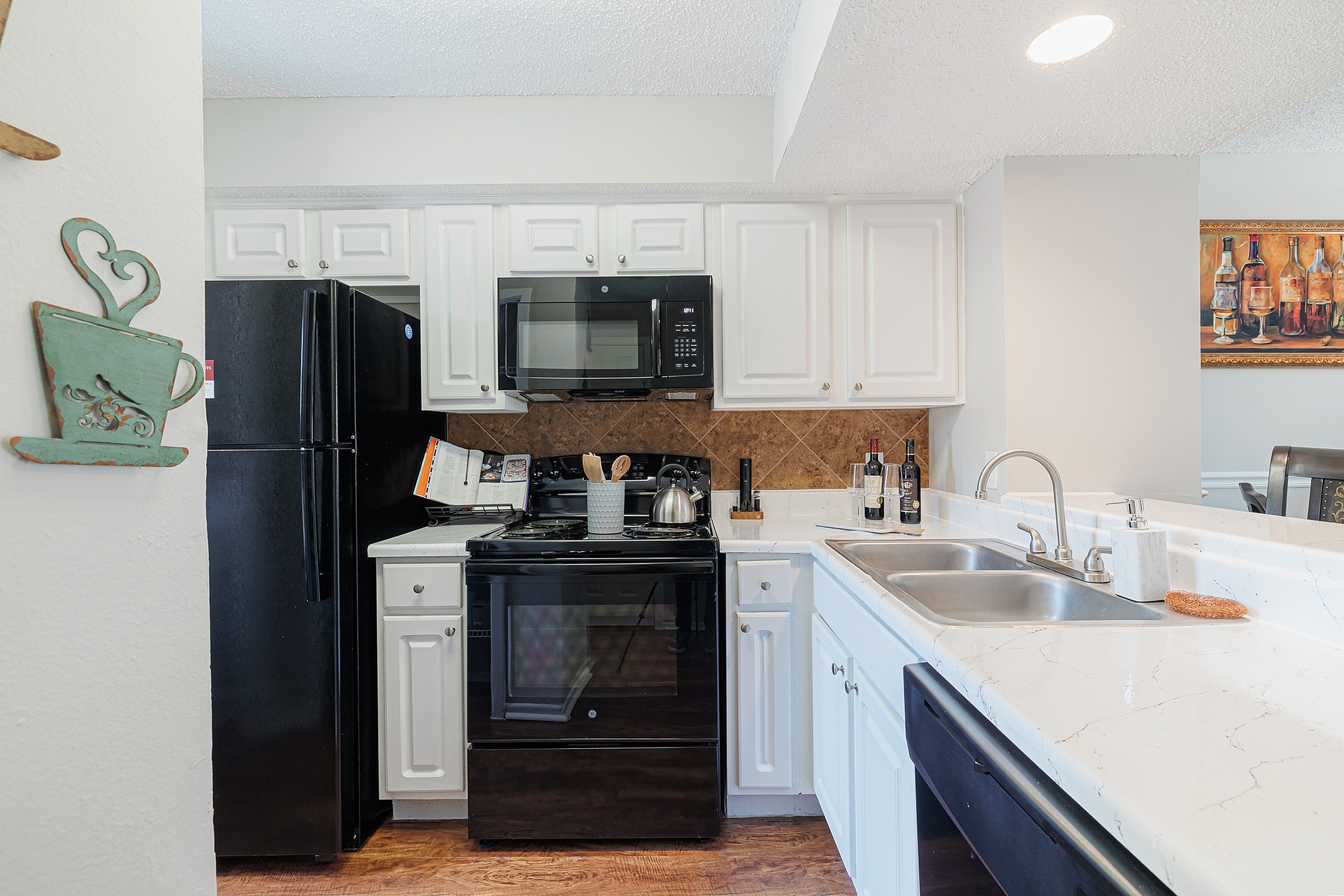 Contemporary kitchen with sleek black appliances, elegant white cabinetry, and a spacious countertop perfect for cooking and entertaining.