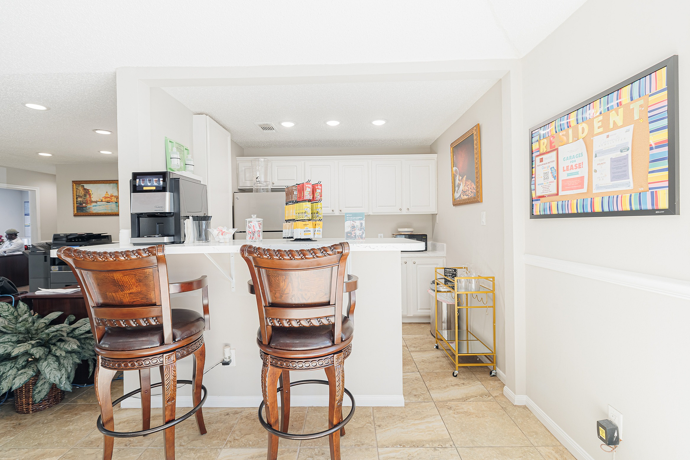 Bright apartment interior featuring a cozy breakfast bar with elegant wooden chairs, a modern coffee maker, and a stylish white kitchen backdrop.