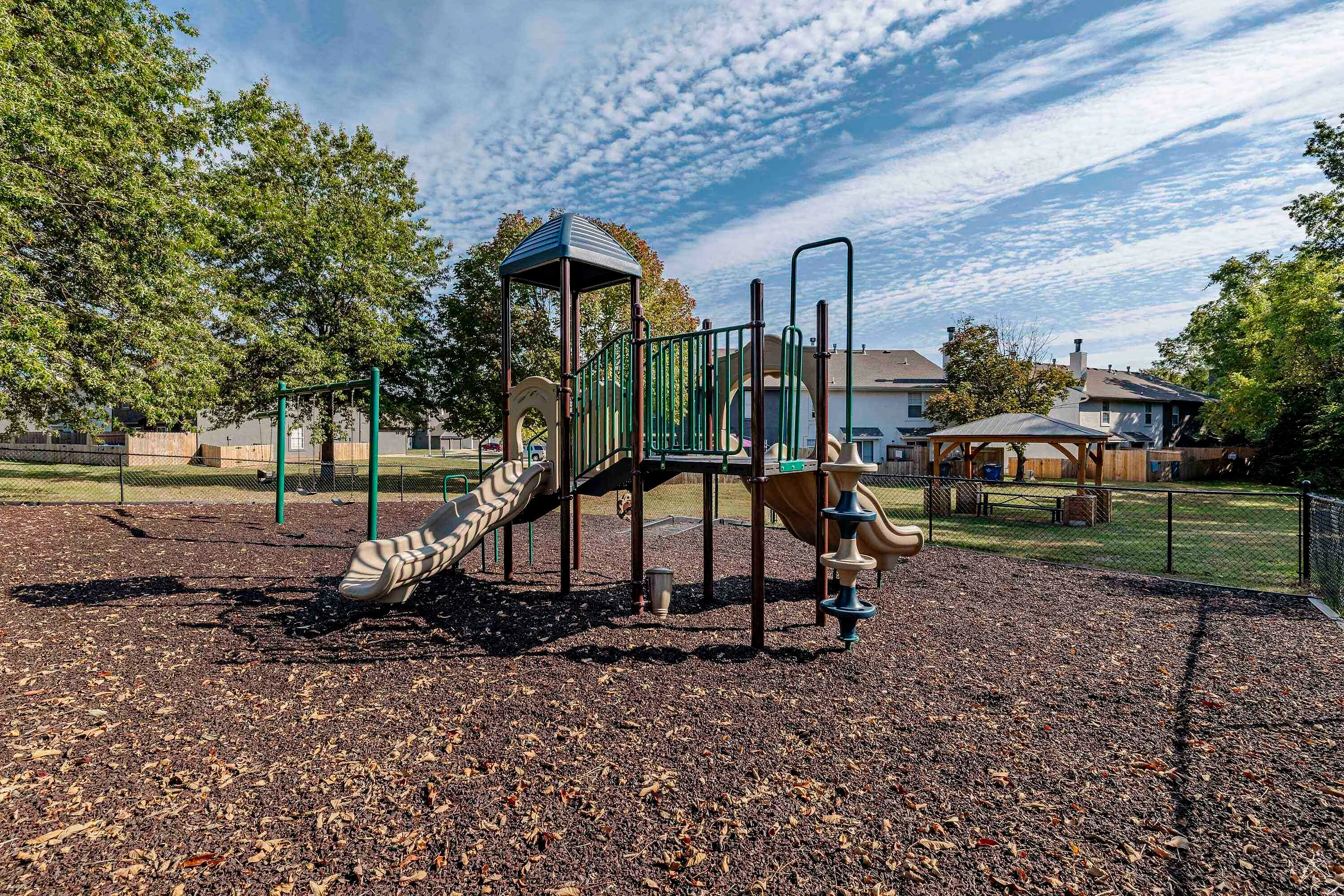 Charming community playground with vibrant equipment set on a sunny day surrounded by lush greenery and a cozy gazebo.