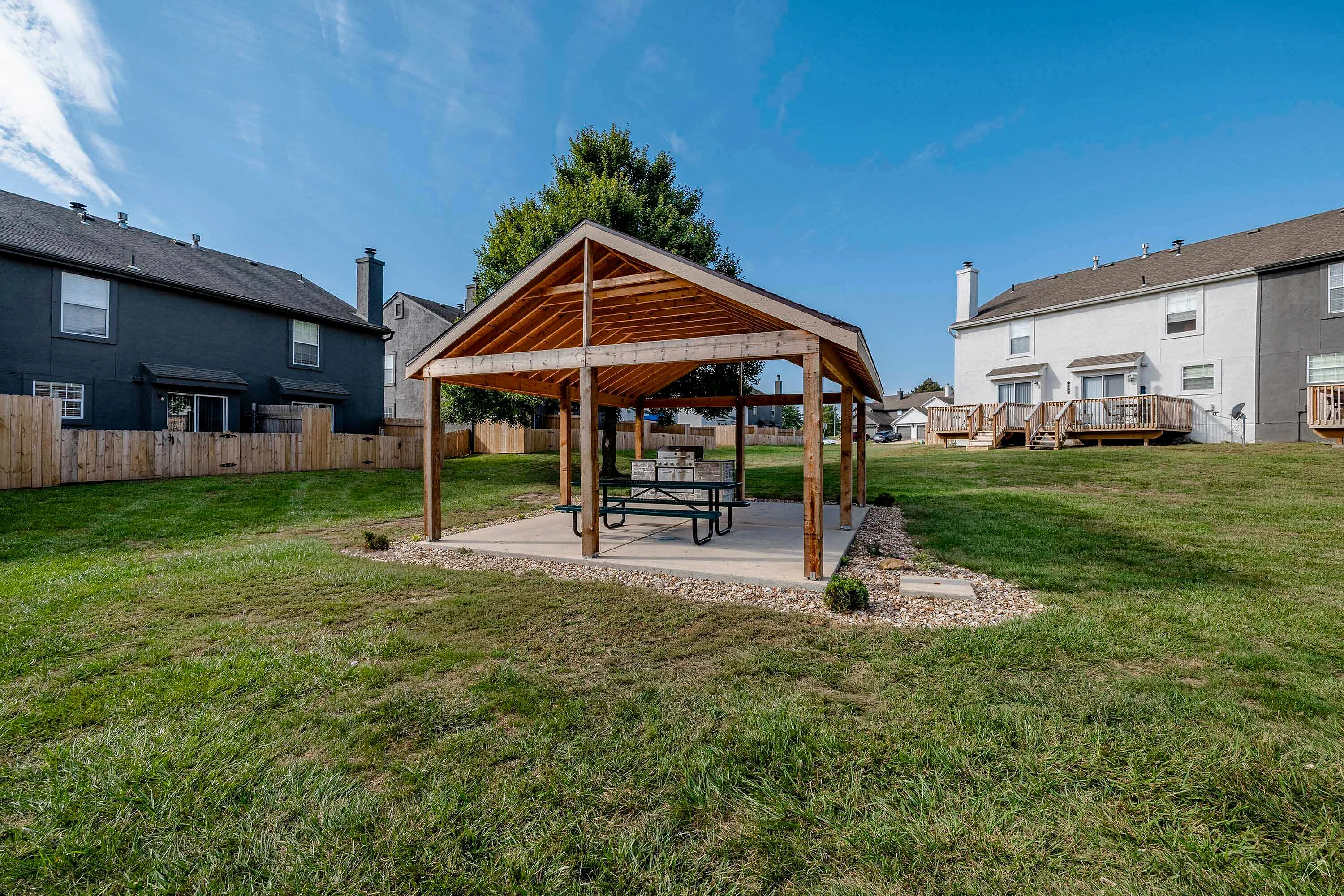 Charming outdoor pavilion with wooden structure set in a spacious grassy backyard, perfect for relaxing and entertaining.